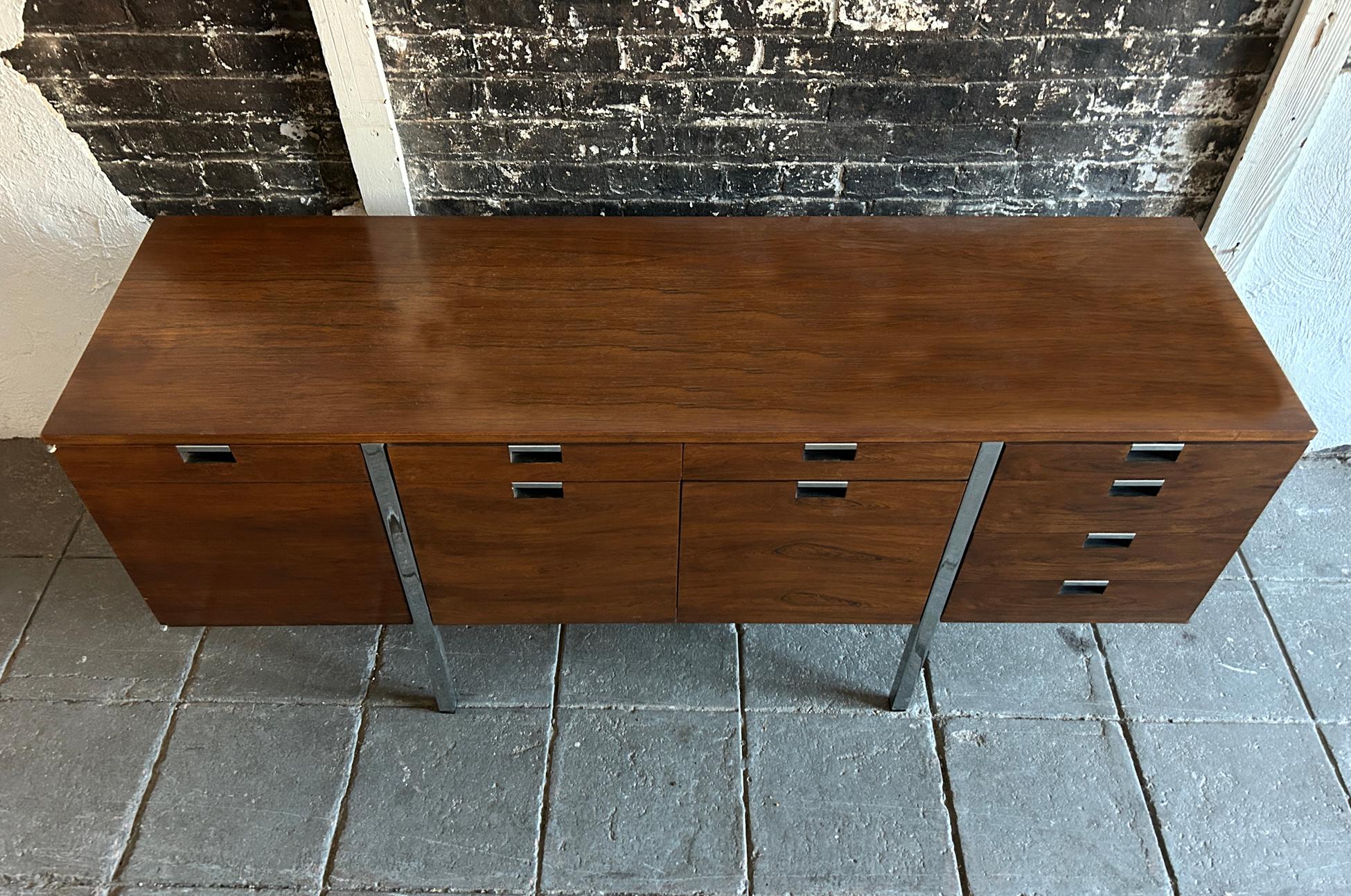Handsome Mid Century credenza designed in the 1970s by Roger Sprunger for Dunbar #1060. Composed of exquisite rosewood veneer and chrome inset pulls and square tube legs. Plenty of storage in a variety of configurations. The far right side features