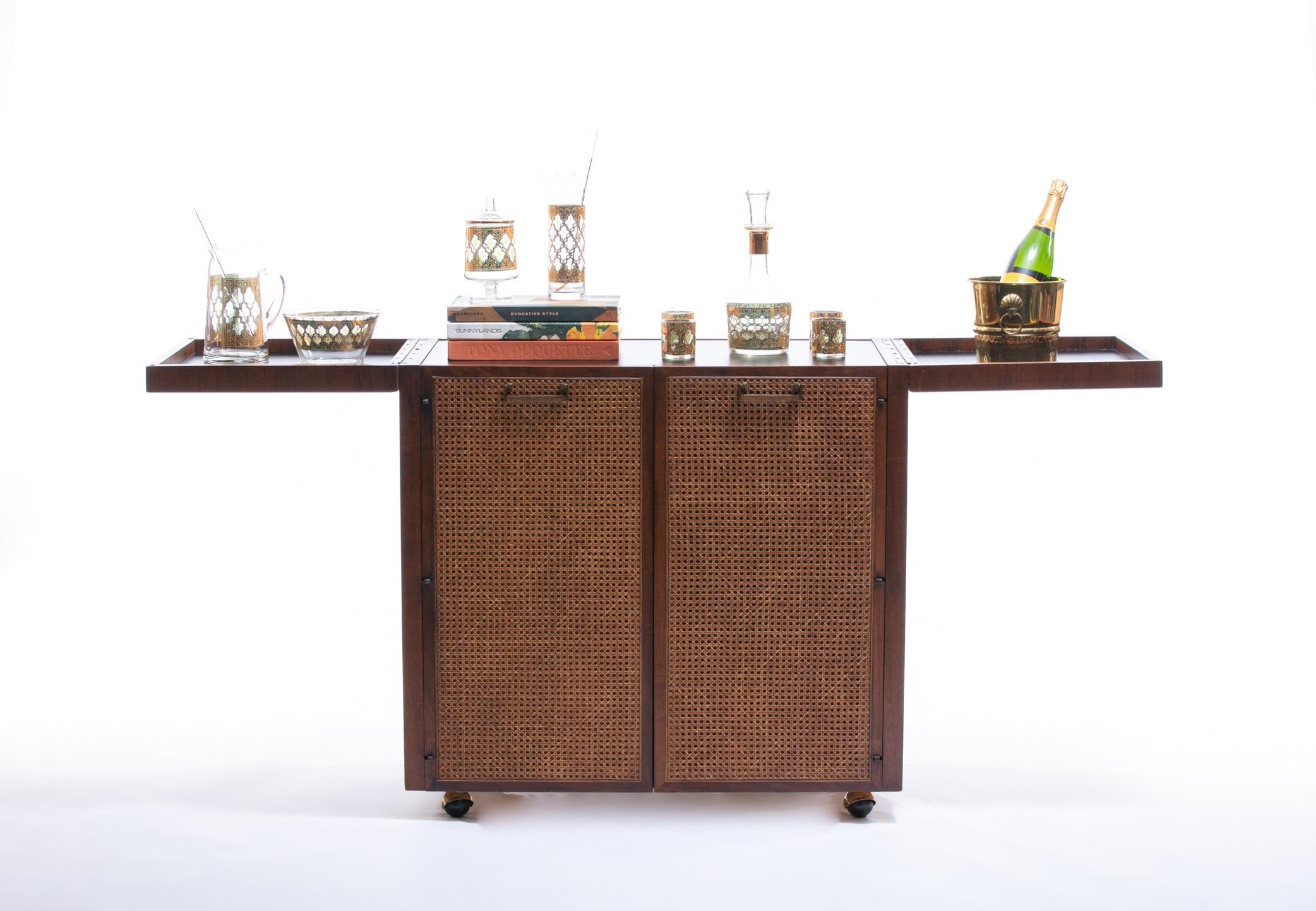 Classic Mid-Century Modern design by Jack Cartwright for Founders featuring a rosewood case, cane-front doors, and brass hardware. This piece was sourced from its original one-owner home and has not moved since new. We styled this bar cart to help