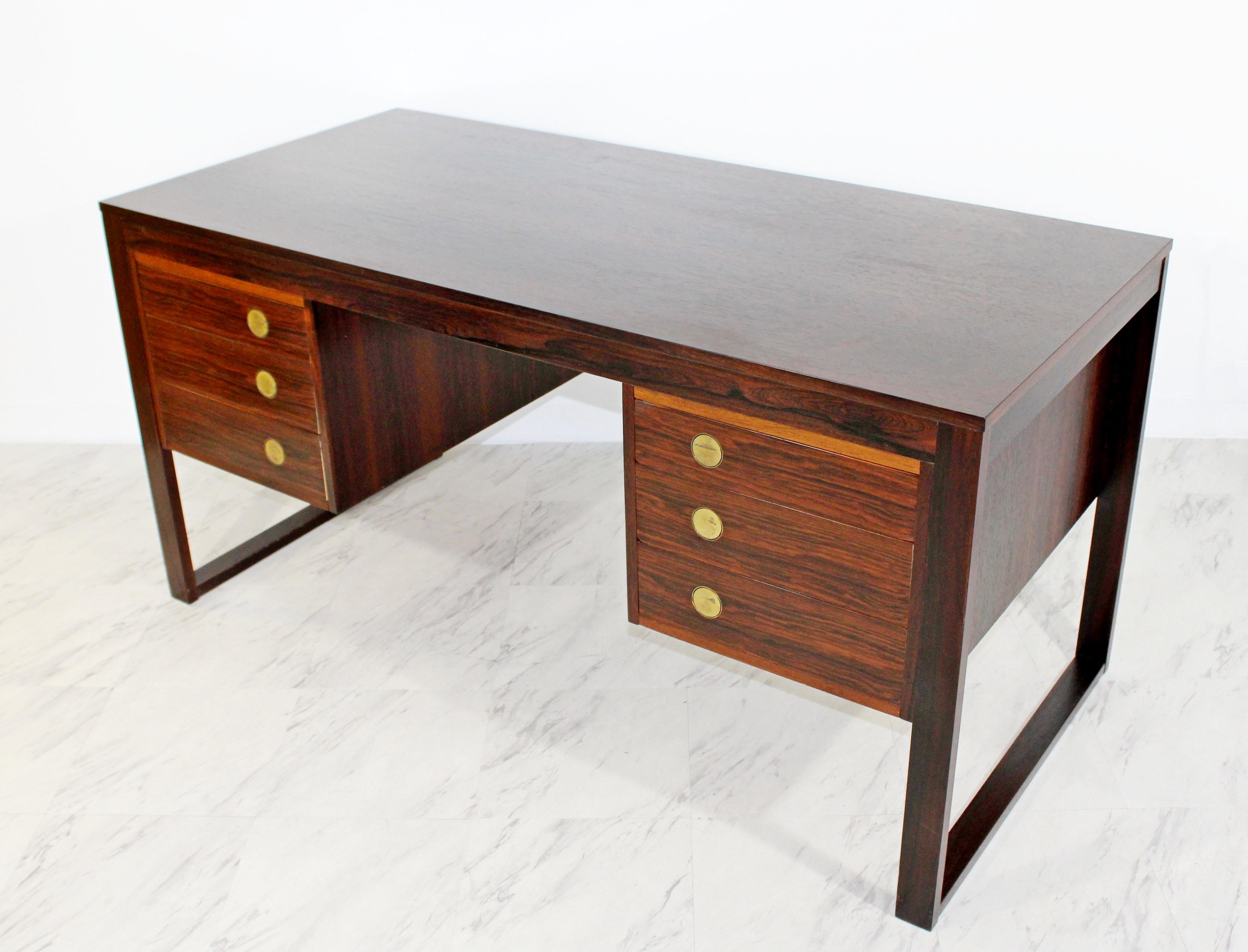 For your consideration is a ravishing, rosewood desk, with six drawers that have brass pulls, by Dyrlund Denmark, attributed to Gunni Omann, circa the 1960s. Has 2 open cabinets in the back for storage. Has unique disc-shaped brass pulls that lay