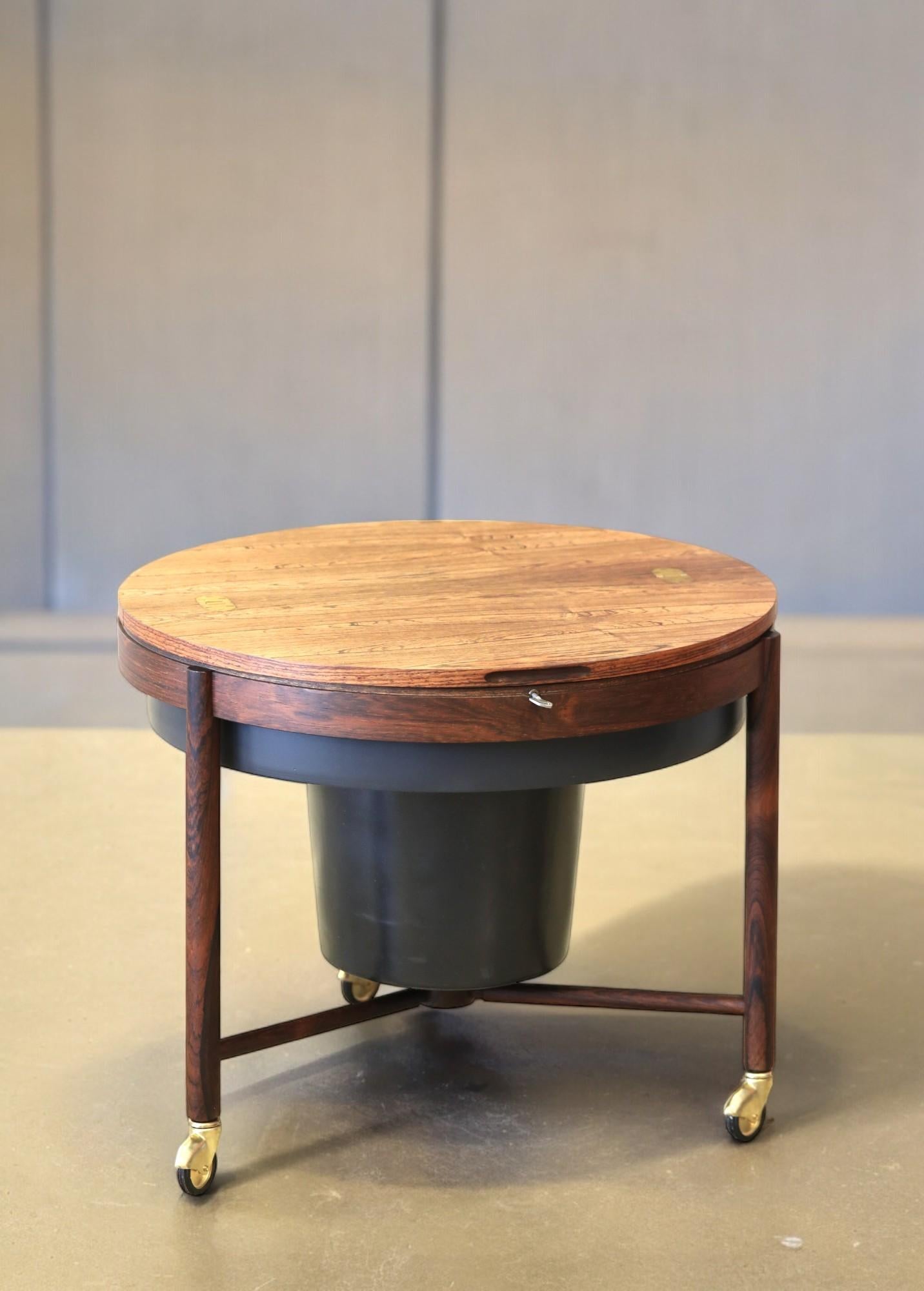 A handy piece of bar furniture that can also be used as a coffee table!

The bar table was designed by Rastad & Relling for Rasmus Solberg in Norway. The table is round and stands on three legs that end with small brass wheels. It makes it easy to