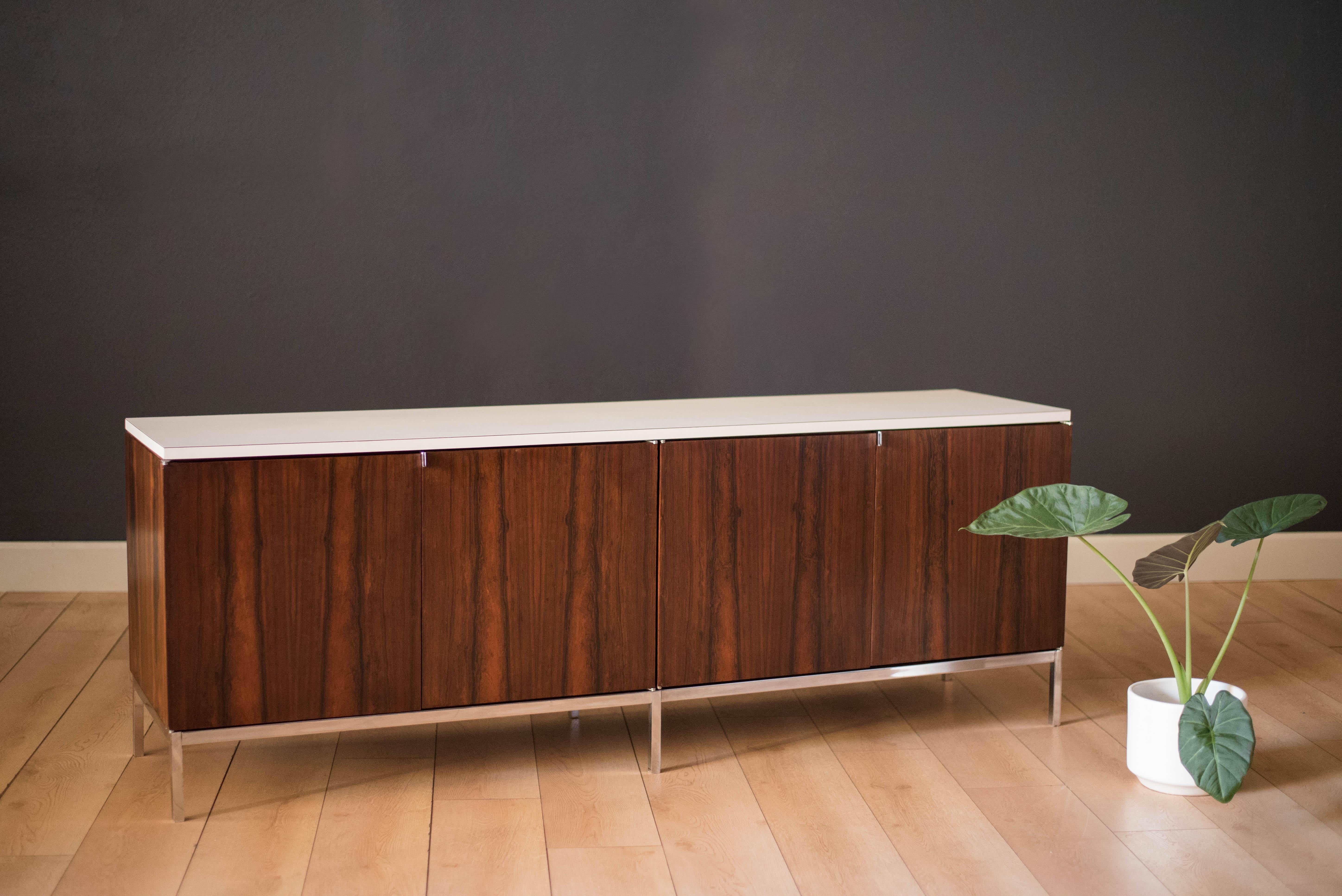 Vintage low credenza or sideboard in rosewood by Florence Knoll, circa 1960s. This piece features the original white laminate top designed for easy maintenance. Includes open cabinet space with adjustable shelving on both sides. Supported by a heavy