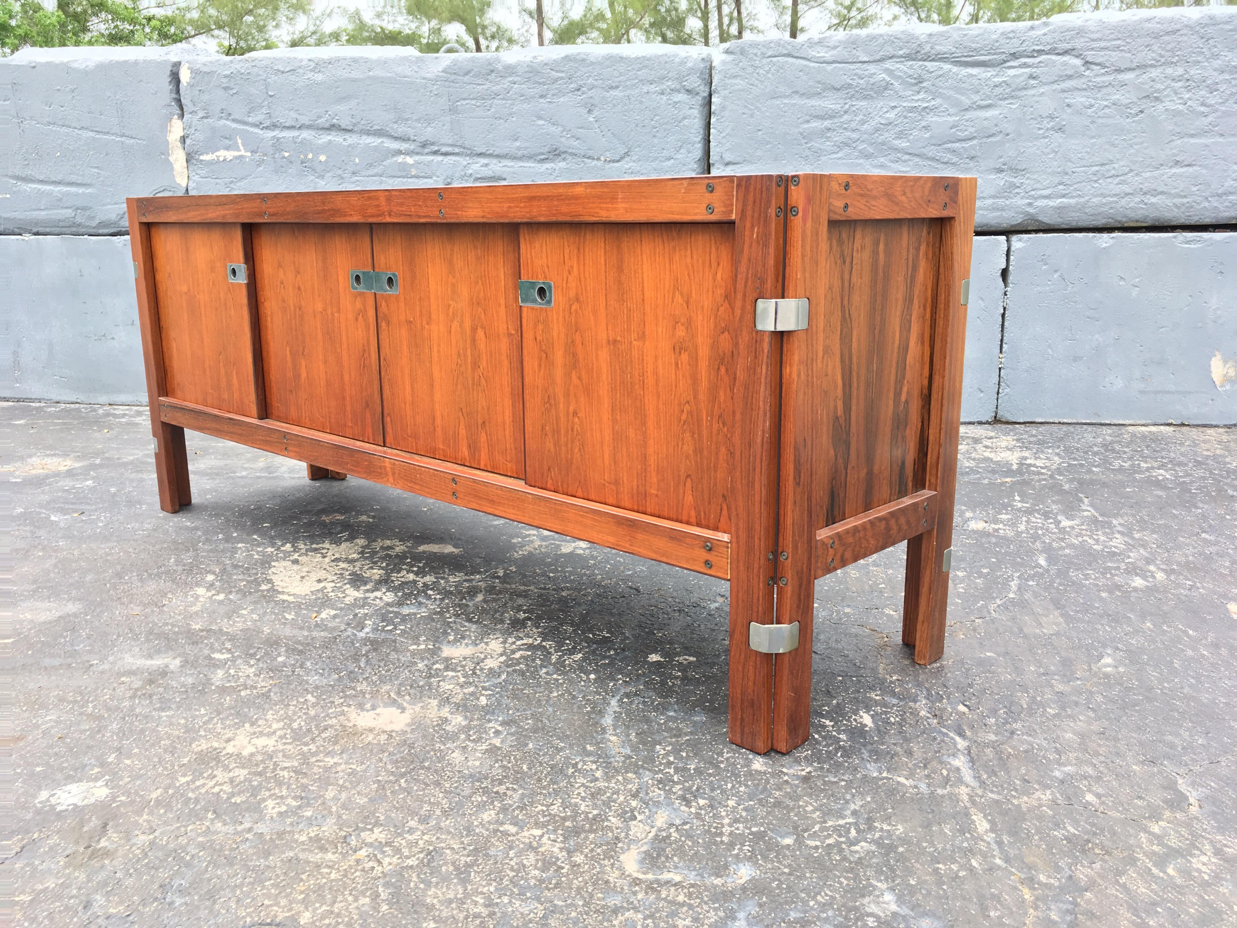 Beautiful Rosewood Credenza with removable hutch. Partly solid and veneered. Hutch is removable and has two glass sliding doors. Bottom credenza has four sliding doors, 4 drawers and two shelves. Height of credenza without hutch is 29.50”.




