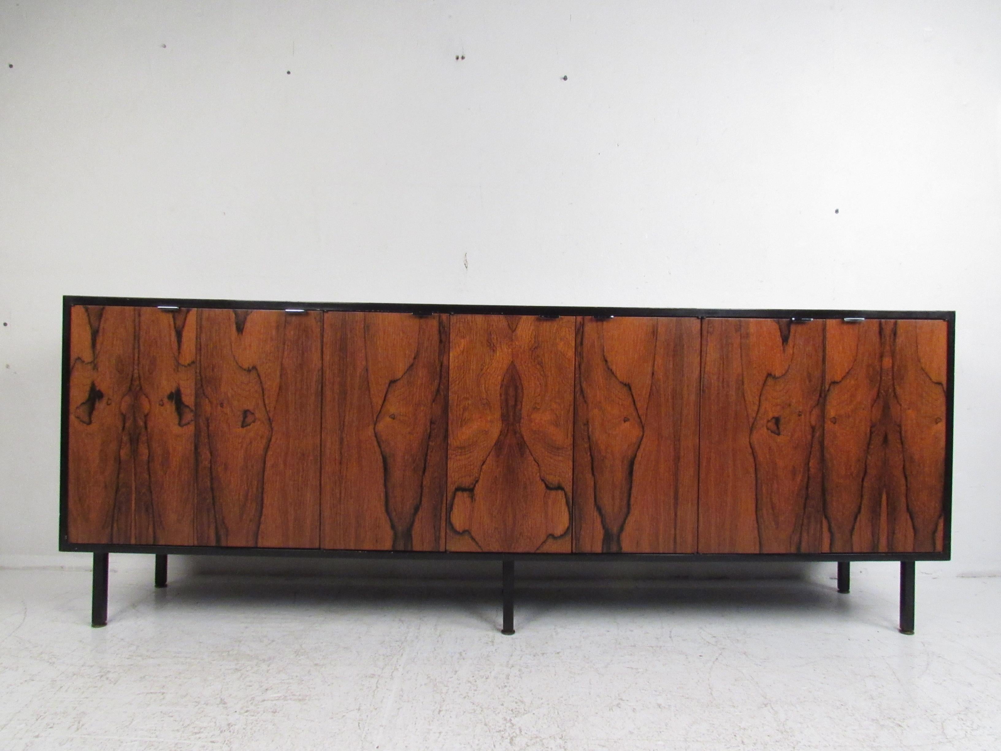 This stunning vintage modern sideboard features a two-tone design with a rosewood front and a black casing. A stylish case piece that provides plenty of room for storage within its hefty drawers and large compartments with shelves. The unique metal