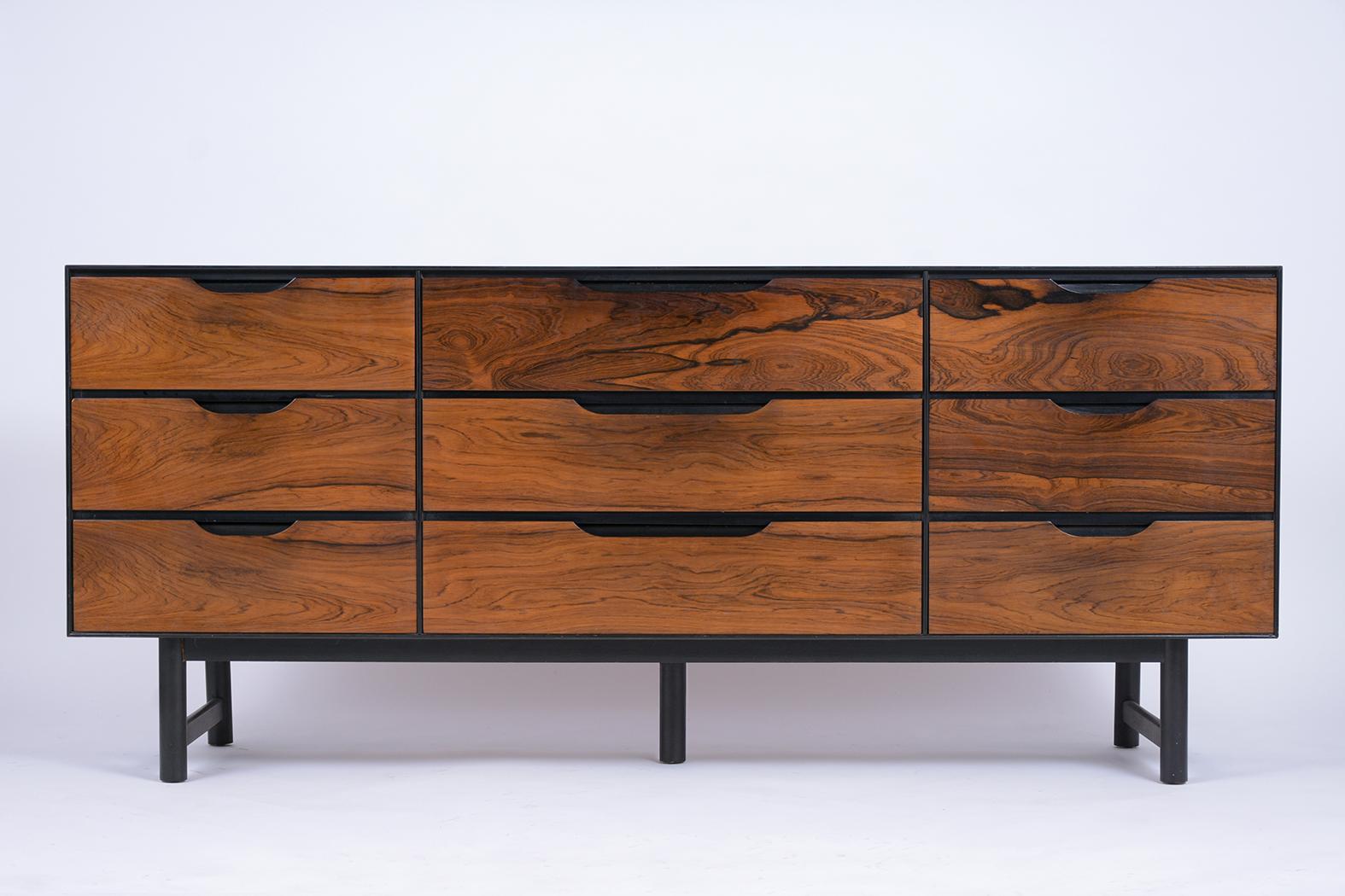 This Mid-Century Modern Dresser is made out of rosewood and has been completed restored. This credenza features an exceptional rosewood grain design, and a newly stained ebonized & rosewood color combination with a lacquer finish. The nine drawers