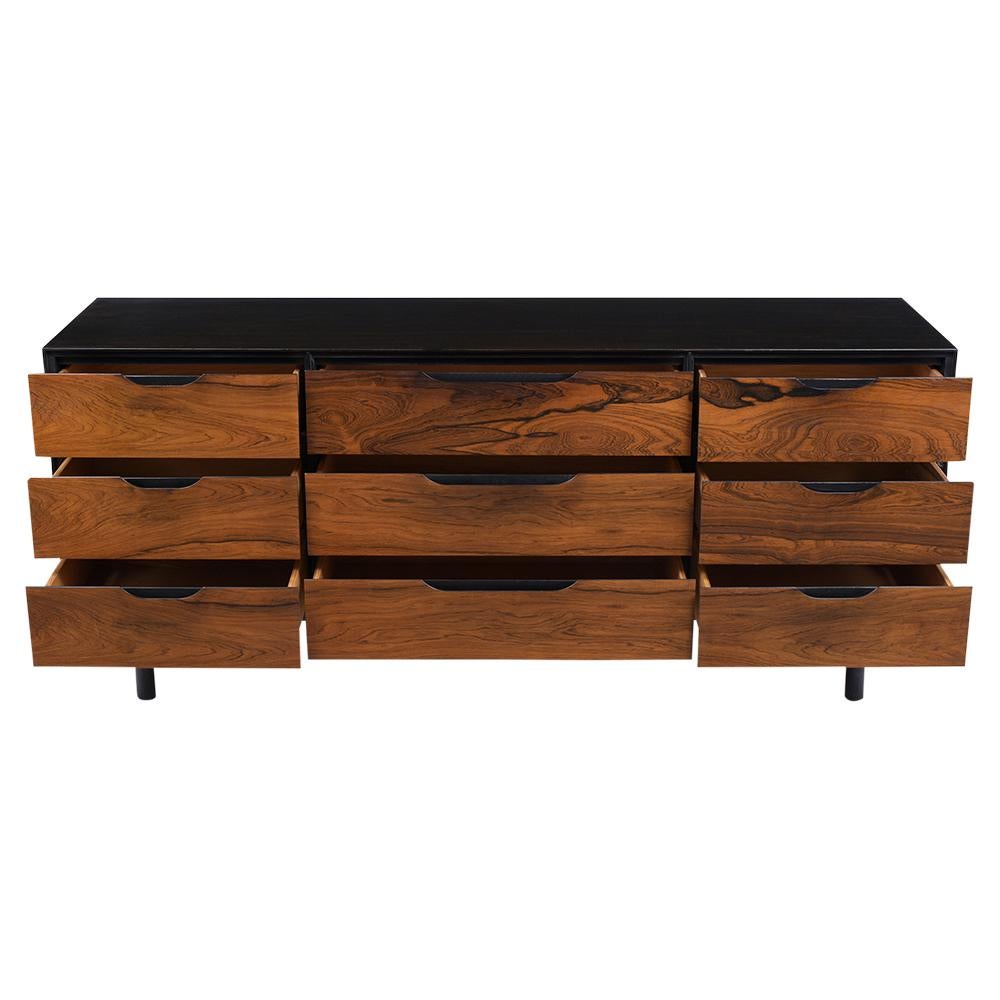 This mid-century modern dresser has been completed restored is made out of rosewood and newly stained ebonized and rosewood color combination with a lacquer finish. This credenza features an exceptional rosewood grain design, nine drawers that have