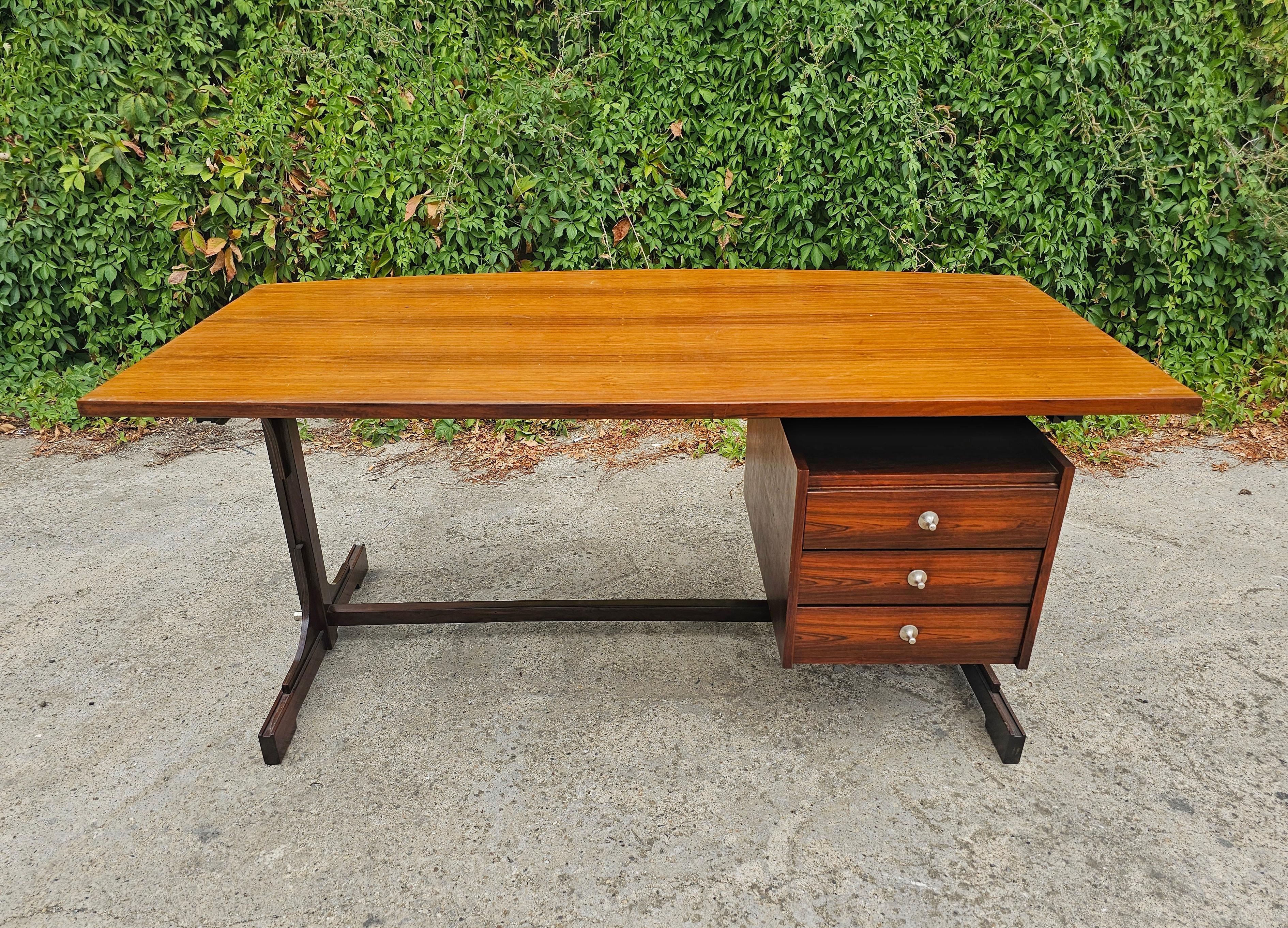 In questo annuncio troverai una spettacolare ed eccezionalmente rara scrivania Mid Century Modern disegnata da Gianfranco Frattini e prodotta da Bernini. Il tavolo è in palissandro. Presenta 3 cassetti e un piano curvo. Il tavolo è presente in G.