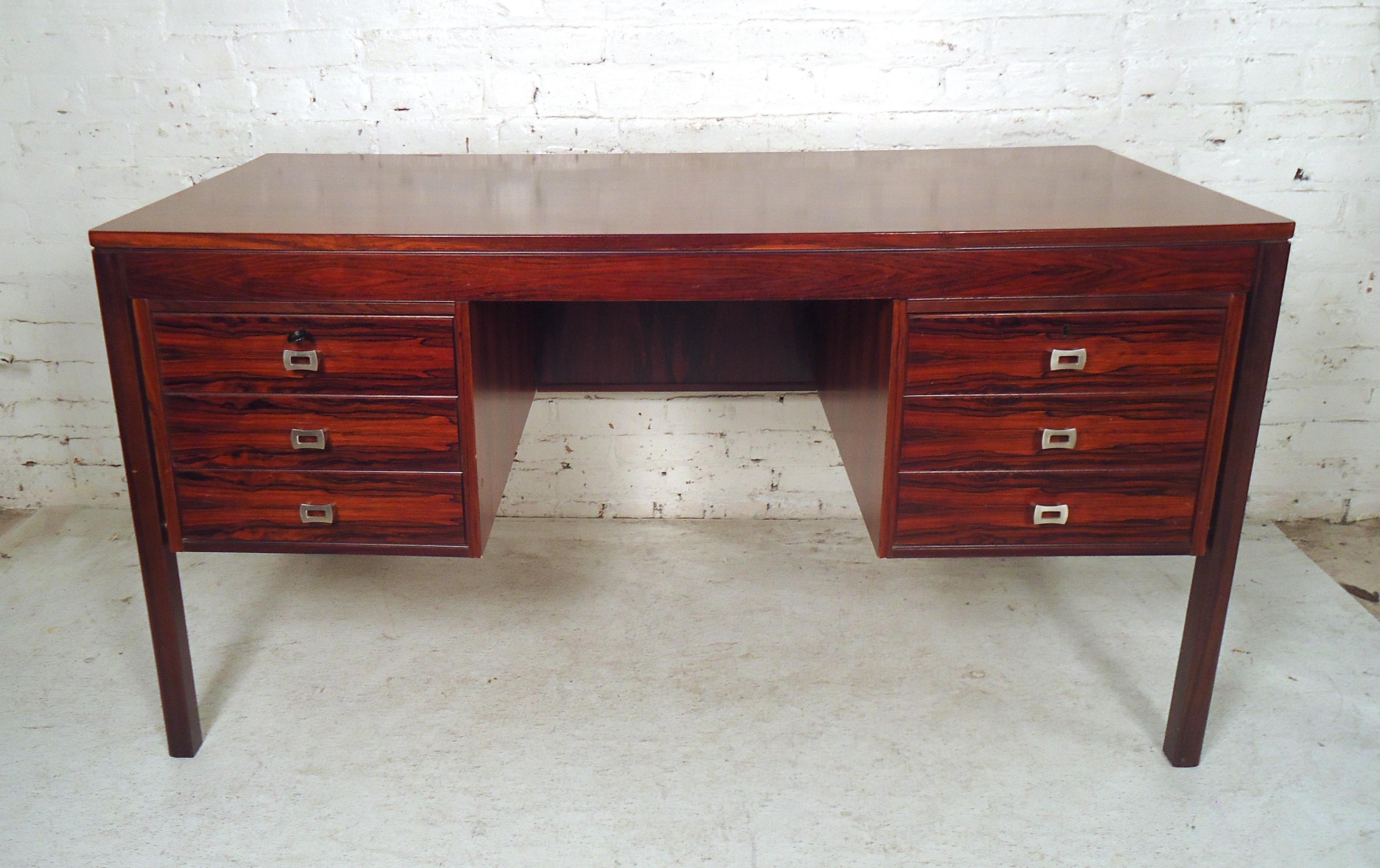 This fantastic midcentury desk features a beautiful Rosewood finish, and sturdy frame. Unique chrome drawer pulls add to the modern style of the piece, while the ample drawer space is perfect for organization. Please confirm item location (NY or NJ).