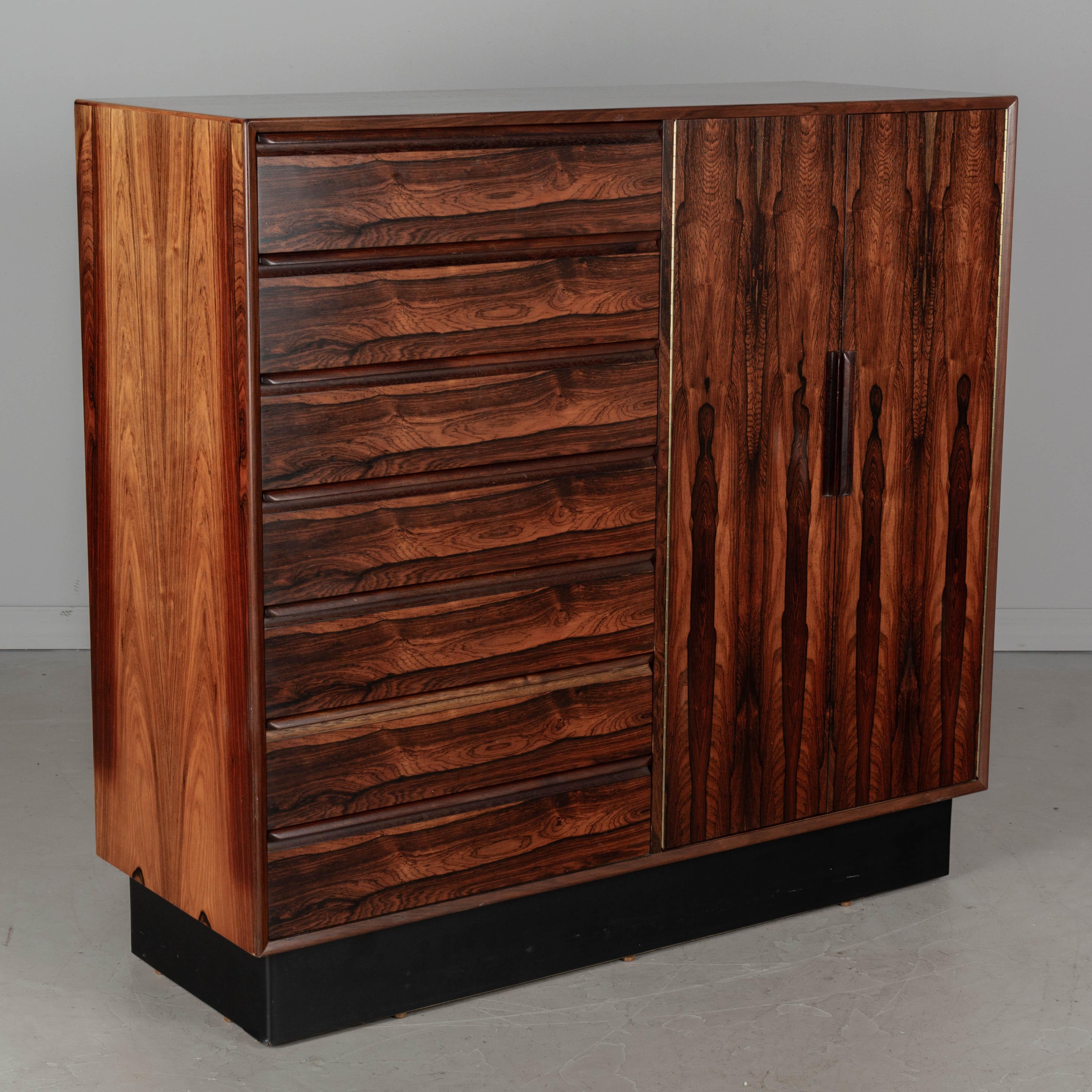 A Midcentury Scandinavian Modern gentleman's chest by Westnofa Furniture. Book matched rosewood veneer with beautifully patterned wood grain. This tall dresser has seven dovetailed drawers on the left and two doors which open to reveal seven