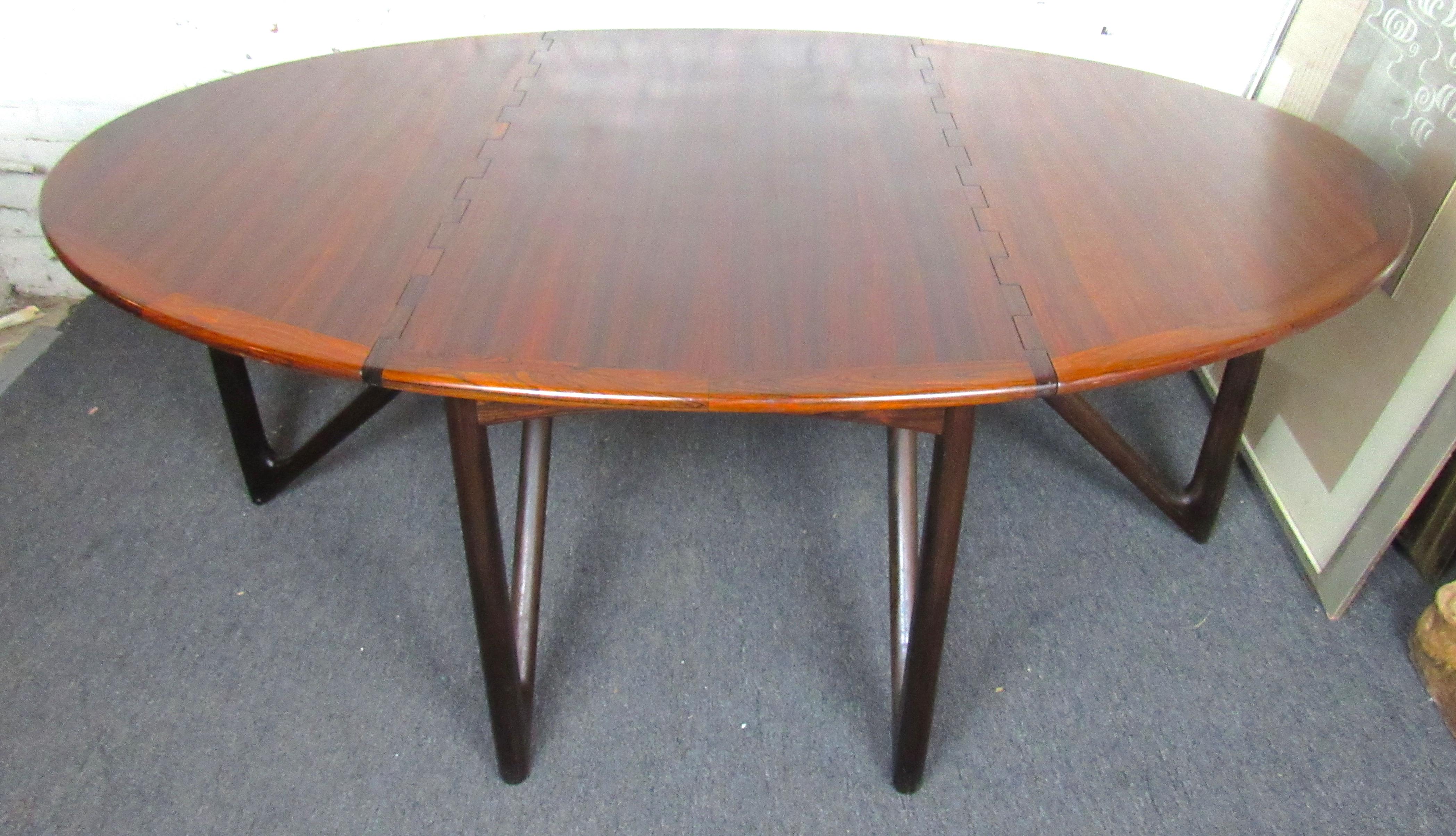 Beautiful Danish vintage modern rose wood dining table designed by Kurt Østervig. This unique table features two large drop leaves that make this table adaptable to groups both large and small. The leaves and center panel are supported by a series