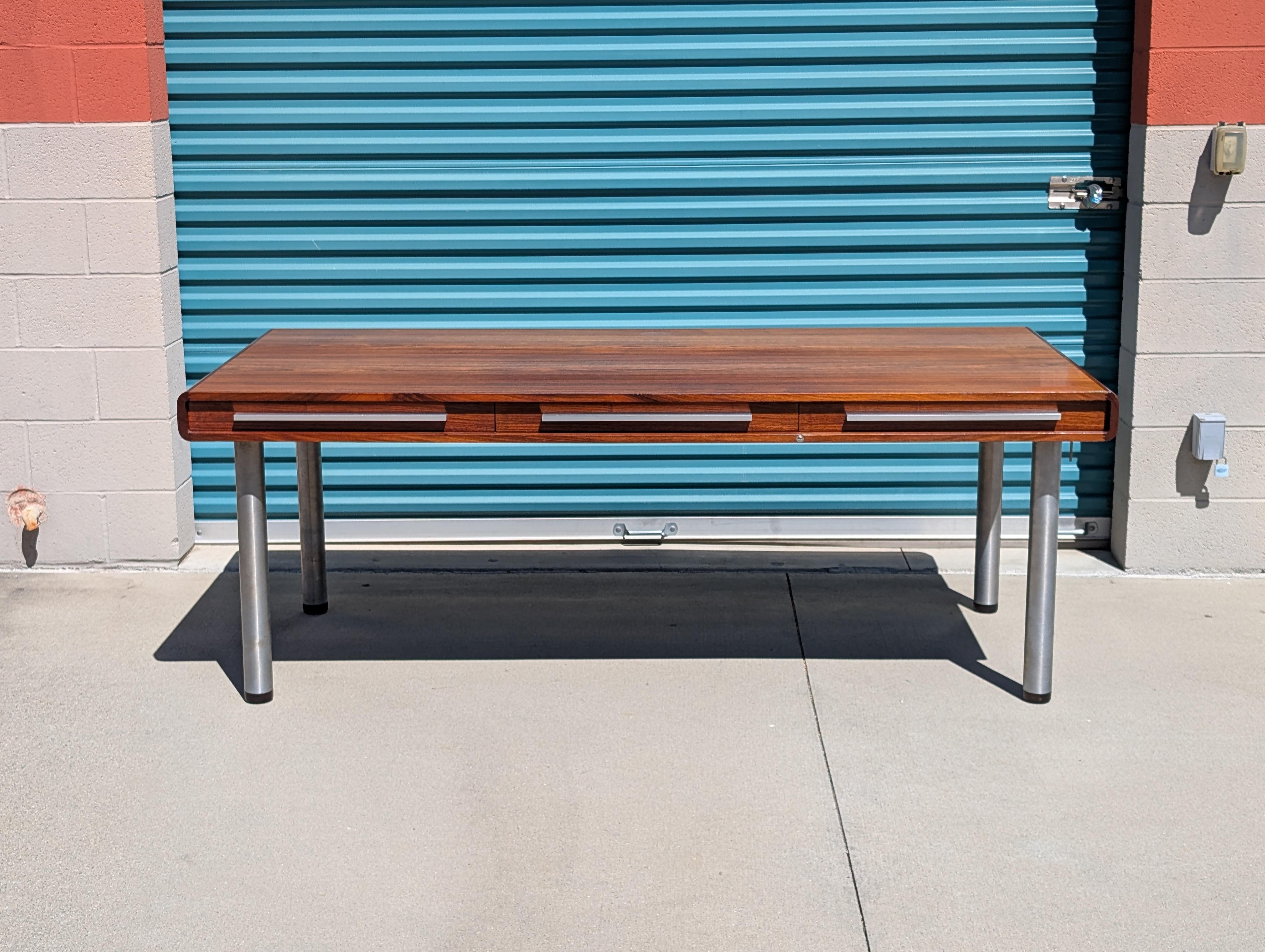 Eleva il tuo spazio di lavoro con questa straordinaria scrivania direzionale danese del Mid Century Modern, realizzata negli anni '70 in palissandro Santos dalla ricca venatura. Questa scrivania, che mette in mostra l'eleganza senza tempo del design