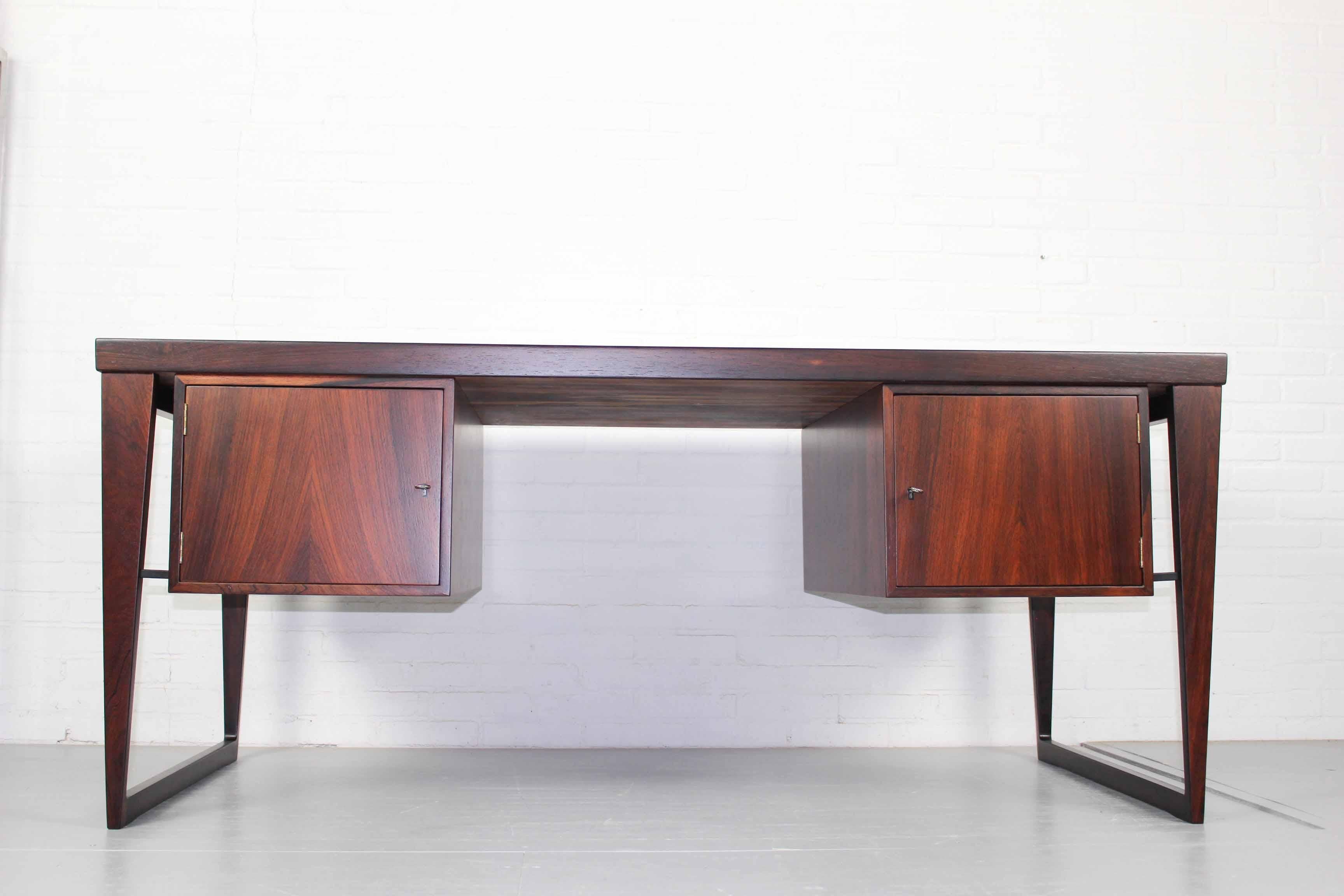 Sophisticated minimalist executive rosewood desk model 70 by Kai Kristiansen for Feldballes Mobelfabrik, 1950s. The desk provides for plenty of storage space with its 6 drawers on the front and 2 doors at the back. The desk looks amazing from all