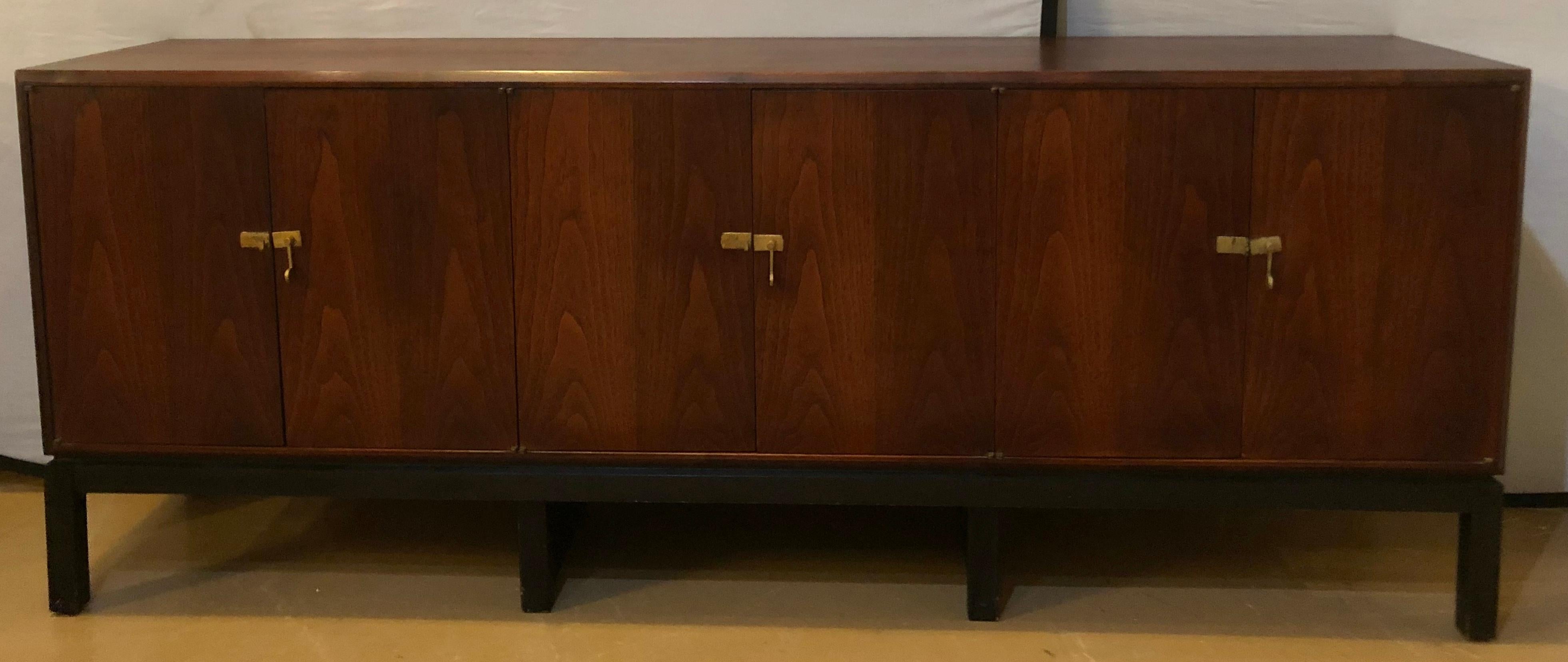 Mid-Century Modern rosewood sideboard/Console with fitted interior on ebony base. This stunning Mid-Century Modern rosewood cabinet sits on ebonized legs with a center opening having fitted drawers flanked by shelved interior side compartments. All