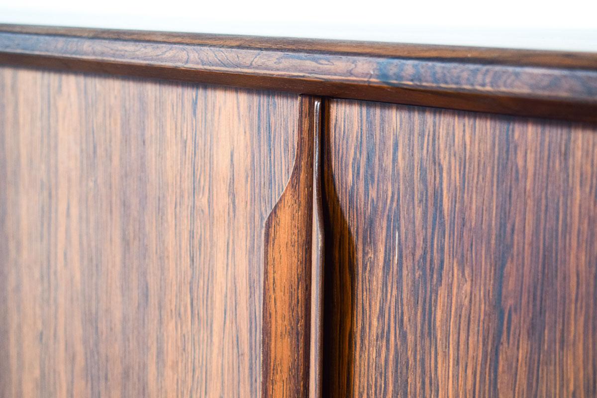 A midcentury modern rosewood sideboard. With four opening doors and stick feet, three trays on the left and a shelf in each of the other three compartments. With elegant lines, beautiful handles, as well as a beautiful grain in the wood. Denmark,