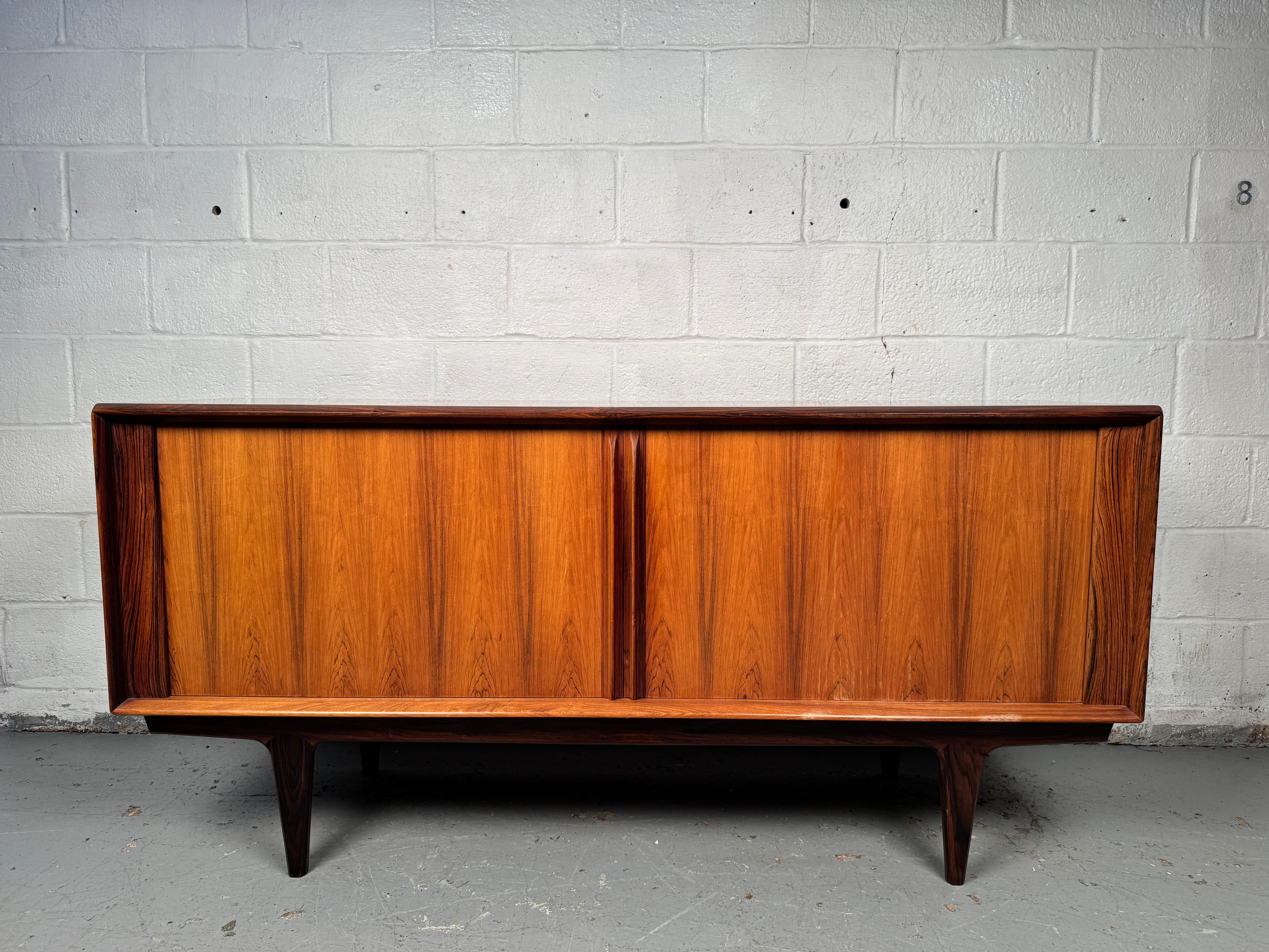 A striking sideboard in richly figured rosewood. Features clean lines, ample storage with cabinet doors and drawers, and beautifully grained surfaces that highlight the natural beauty of rosewood. A timeless statement piece with both form and