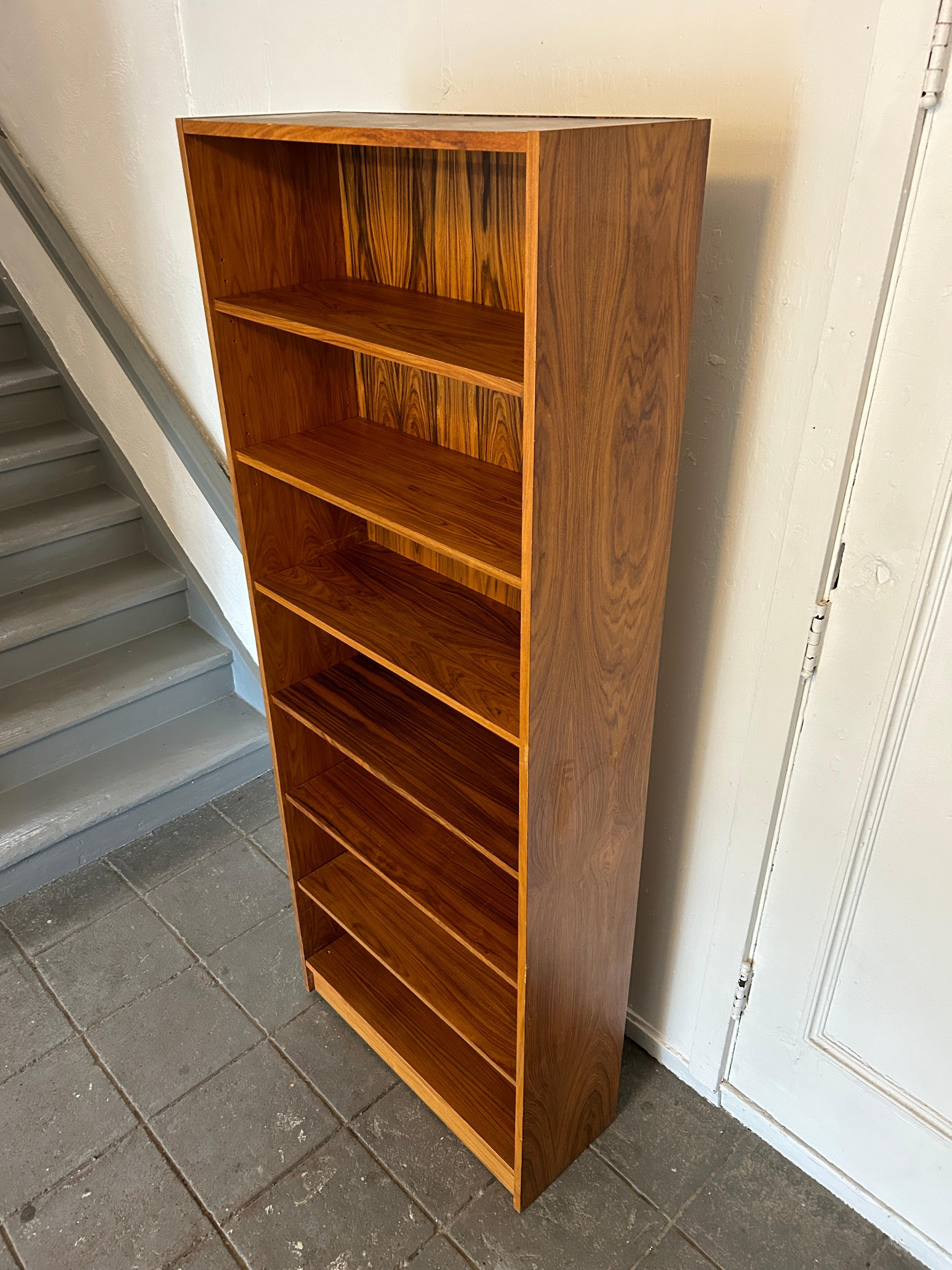 Stunning rosewood tall bookcase. This bookcase is completely original and in very good vintage condition. The bookcase has (5) adjustable shelves. Beautiful rosewood grain. The rosewood Grain is pretty amazing. by Gritsch Brazil. Labeled on