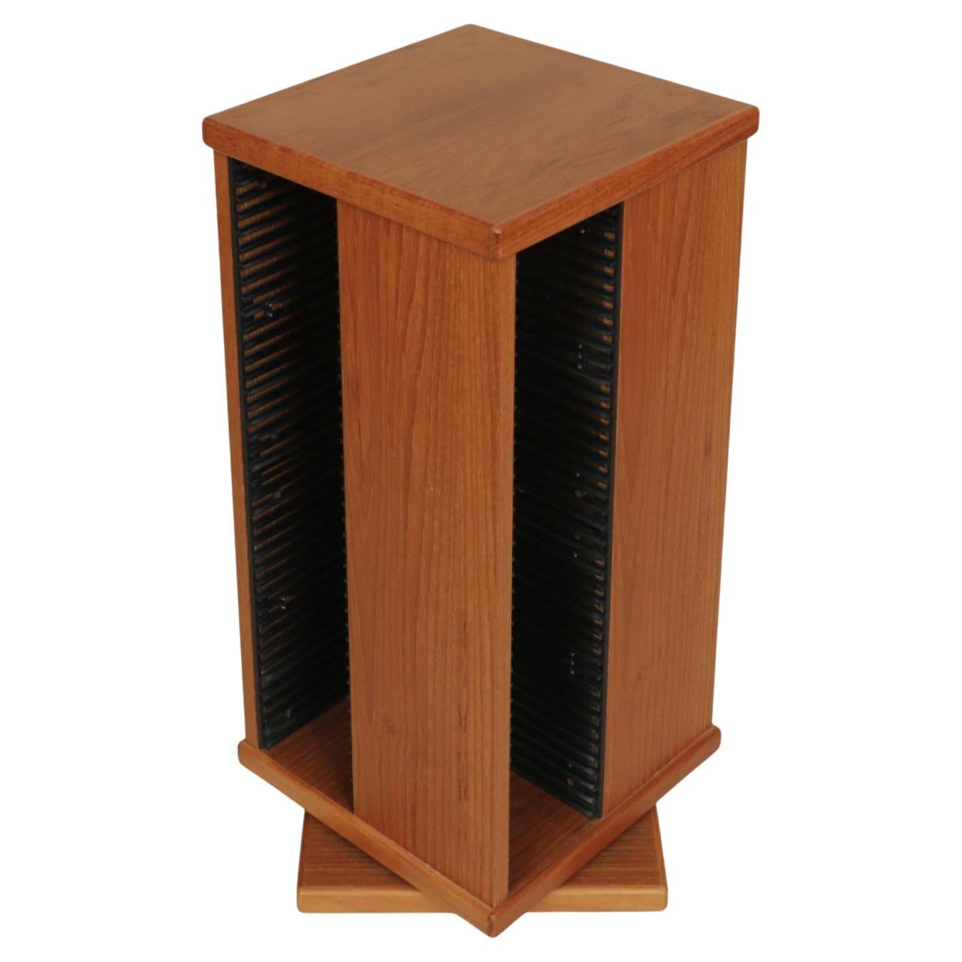 A mid-century modern rotating CD rack made by Design Furniture Manufacturing of Ontario, Canada. Made of maple, the square tower has openings with black metal CD racks to the left of each side. Holds 160 CD's total (40 in each side). Marked ‘Made in