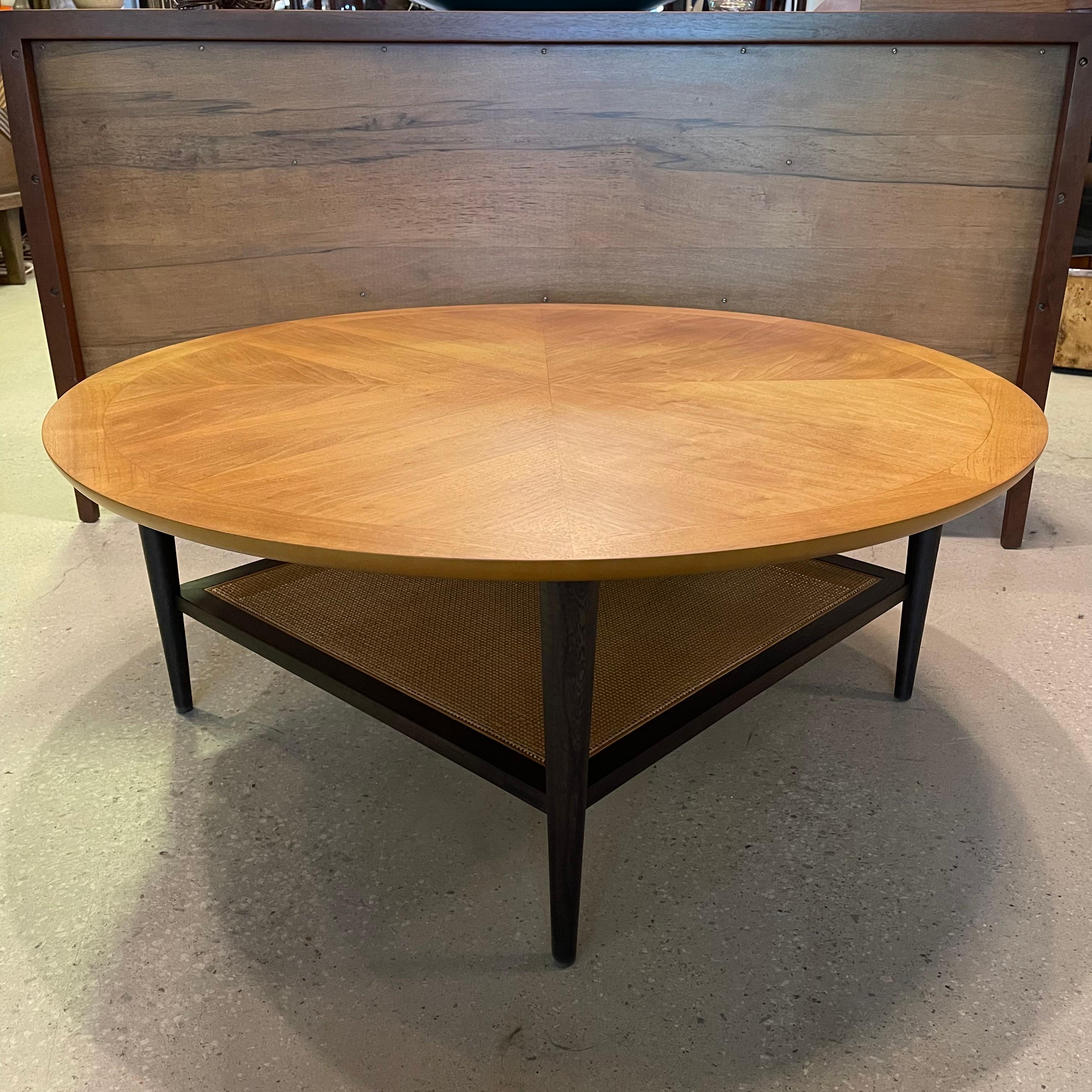 Mid-century modern, walnut coffee table by Lane Alta Vista features a custom cFsignature finish. The round, book-matched grain top with border trim is bleached contrasting with the ebonized base that highlights the natural cane lower shelf. The