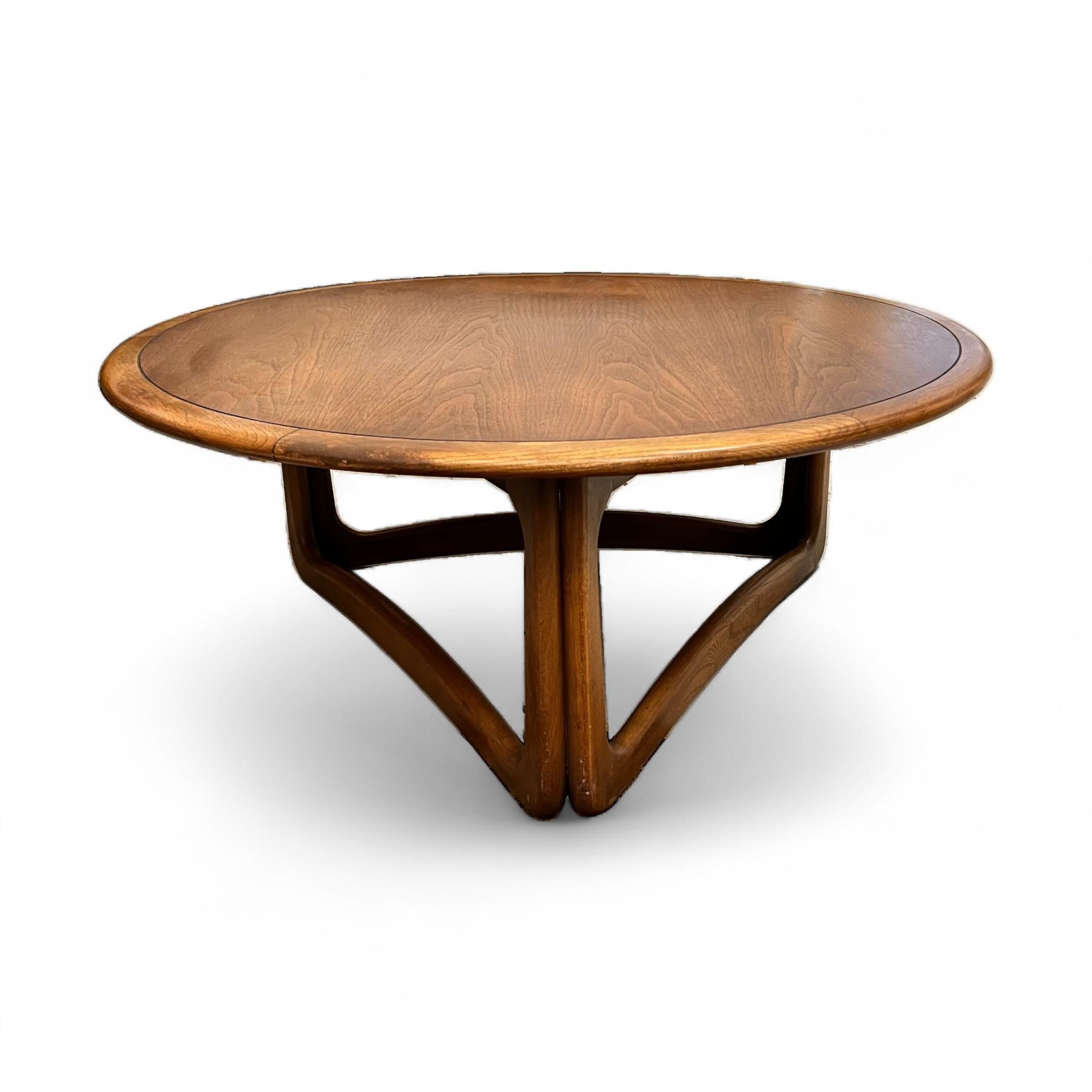 Esta llamativa mesa de centro Moderna de Mediados de Siglo presenta un rico acabado en nogal con un tablero redondo que exhibe bellos detalles de vetas de madera en cuadrante. Su escultural base geométrica añade interés arquitectónico y estabilidad,