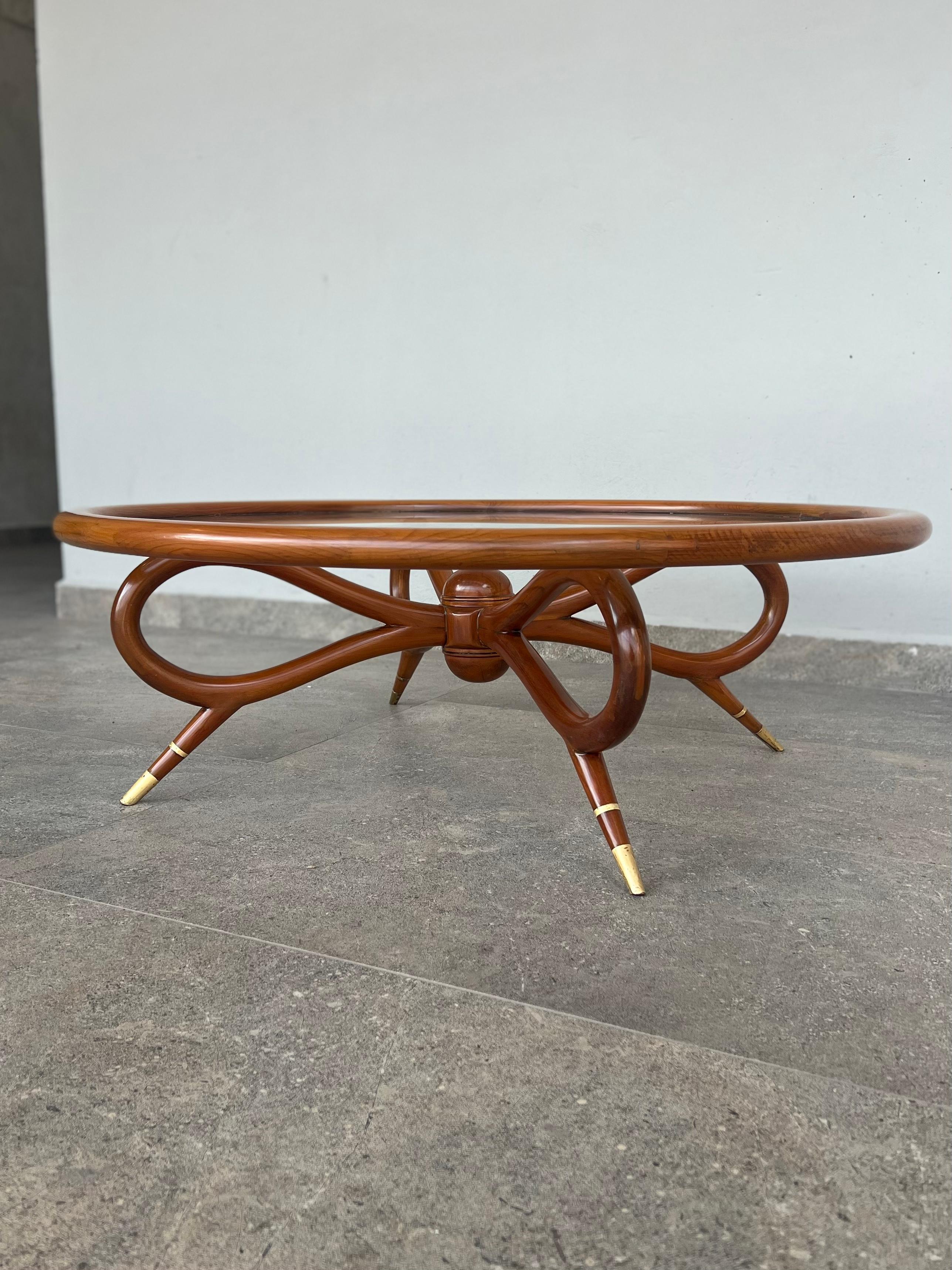 A coffee table that is not seen very often, its shape makes it unique, domed wood in the shape of a bow, one meter in diameter with its glass embedded in the wood, without saying much because at first glance it says it all.