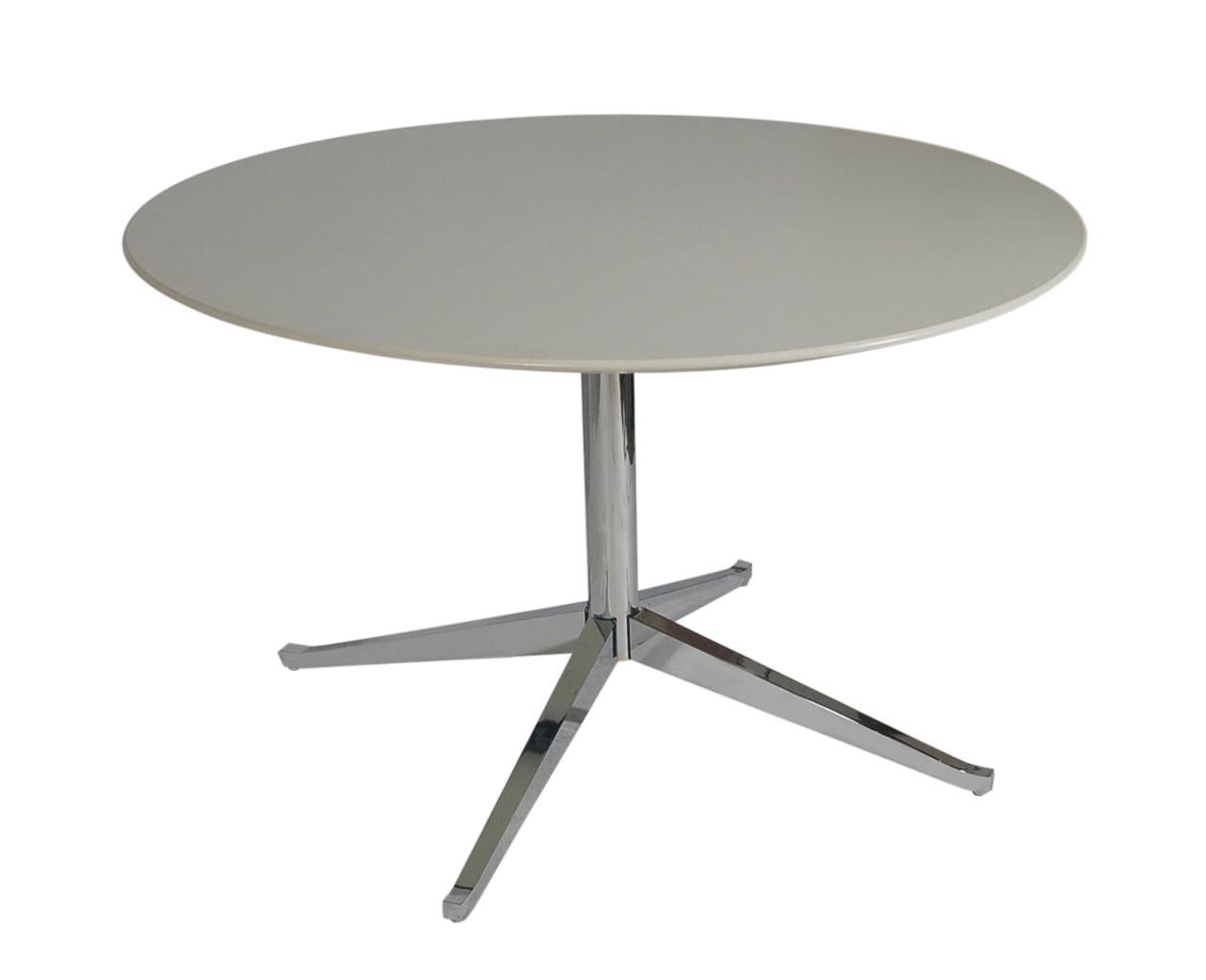 A Classic Minimalist design from Florence Knoll and produced by Knoll in the 1990s. The table features a chrome-plated solid steel base with a white laminate circular top. Manufacturers stamp to base.