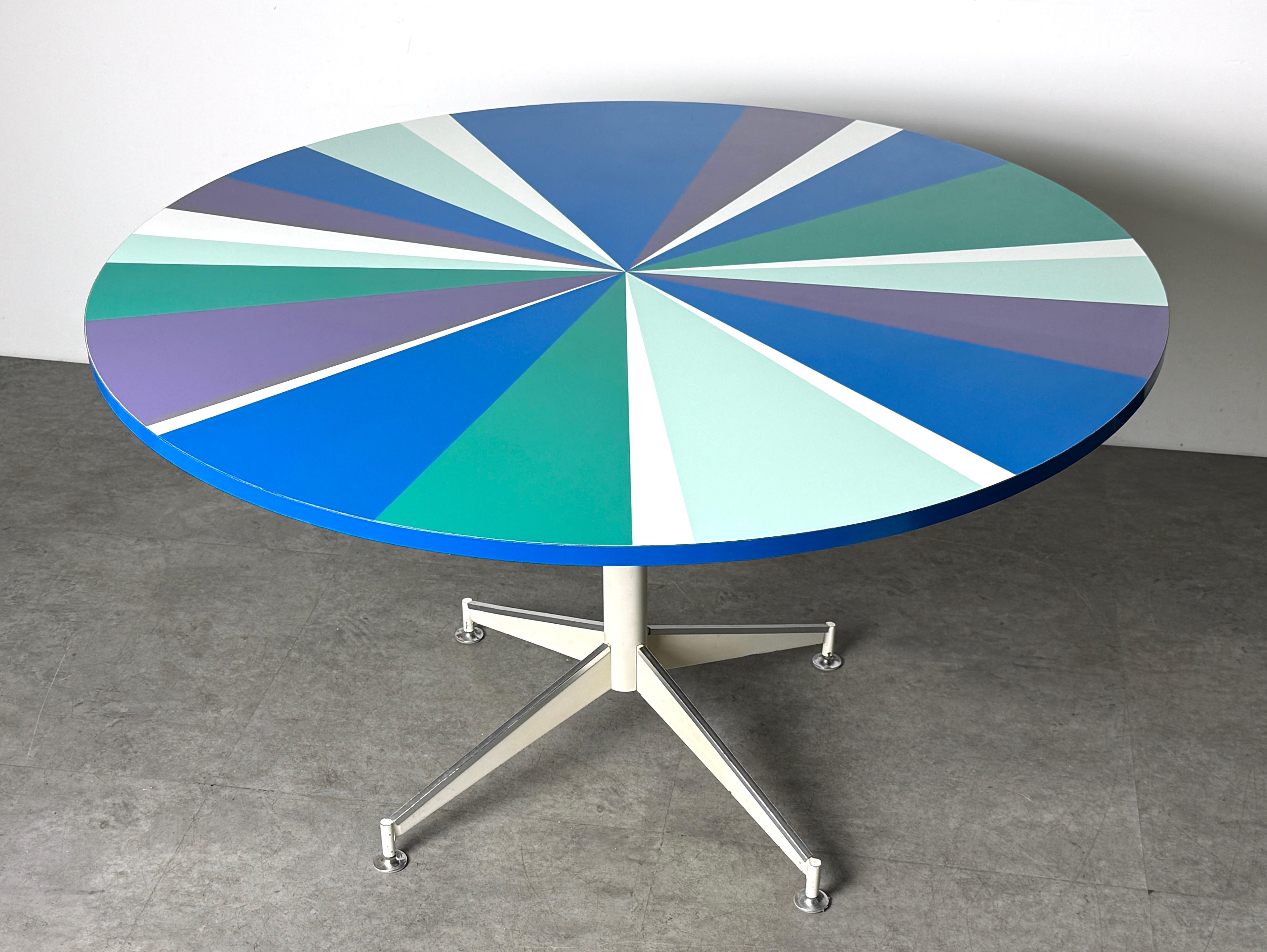Rare table de salle à manger moderniste de Peter Pepper Products
USA circa 1960's

Surface stratifiée ronde avec motif de roue d'épingle en violet, bleu et vert
Socle à quatre étoiles en métal émaillé blanc avec garniture en aluminium.

Diamètre de