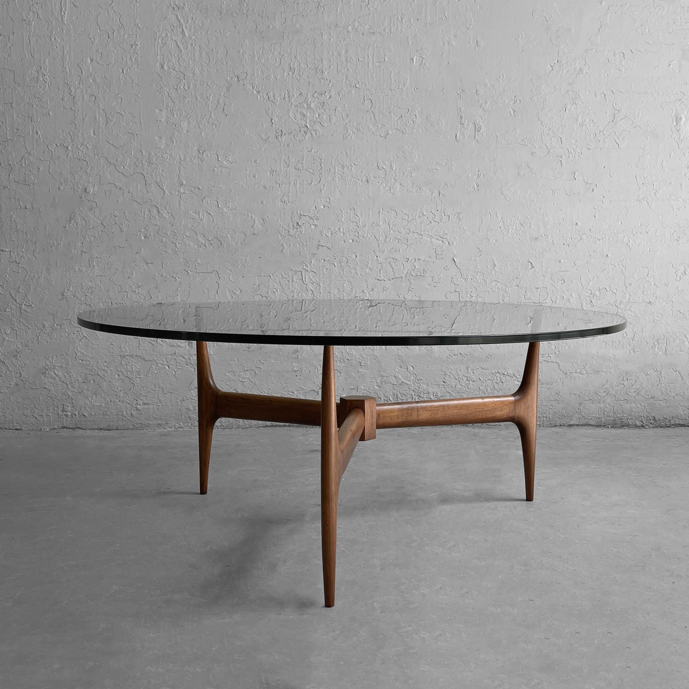 Elegant, Mid-Century Modern coffee table features a sculptural walnut tripod base with 36 inch round glass top. The top rests on the base.