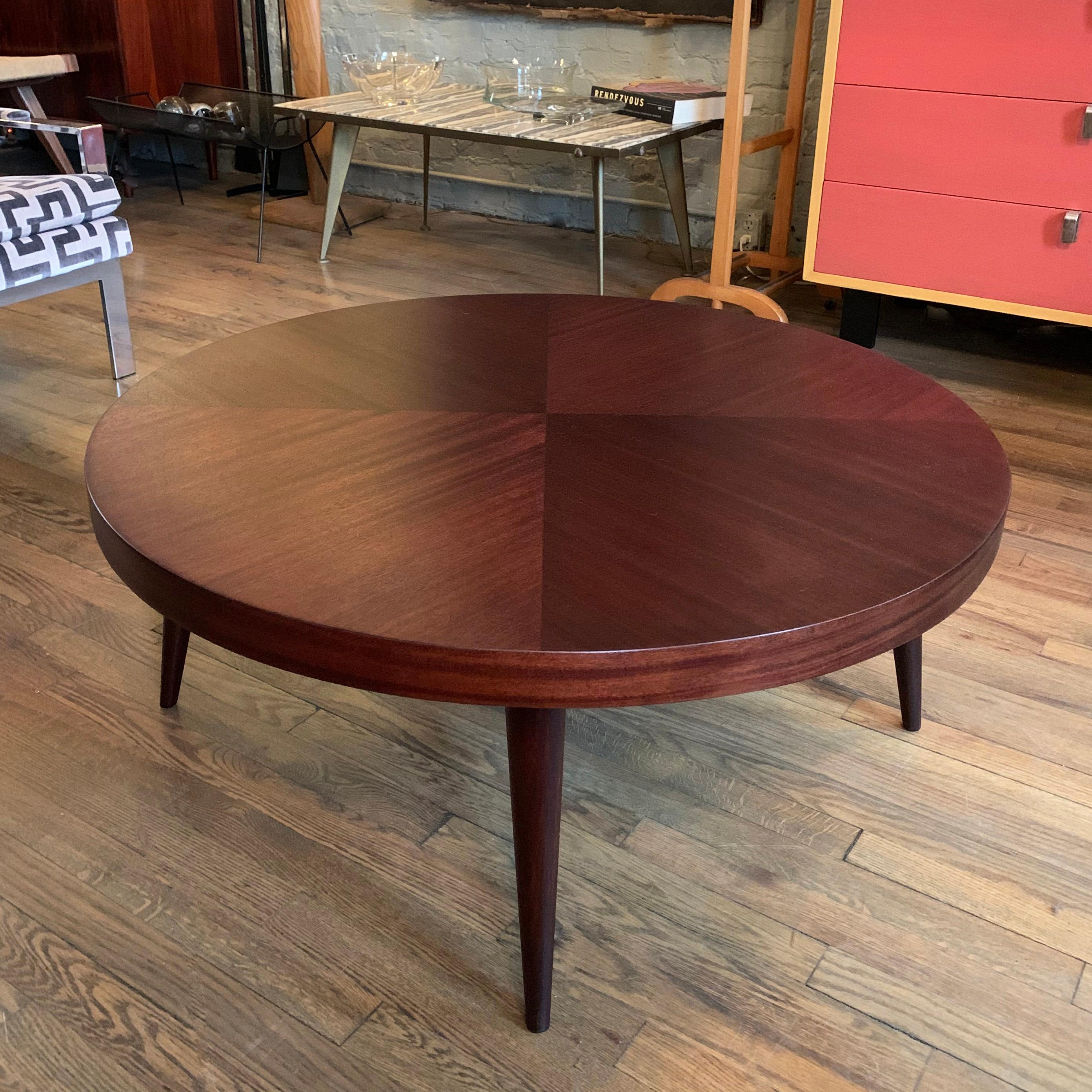 Mid-Century Modern, low, round, mahogany coffee table features a contrasting grain detail on top and tapered legs.