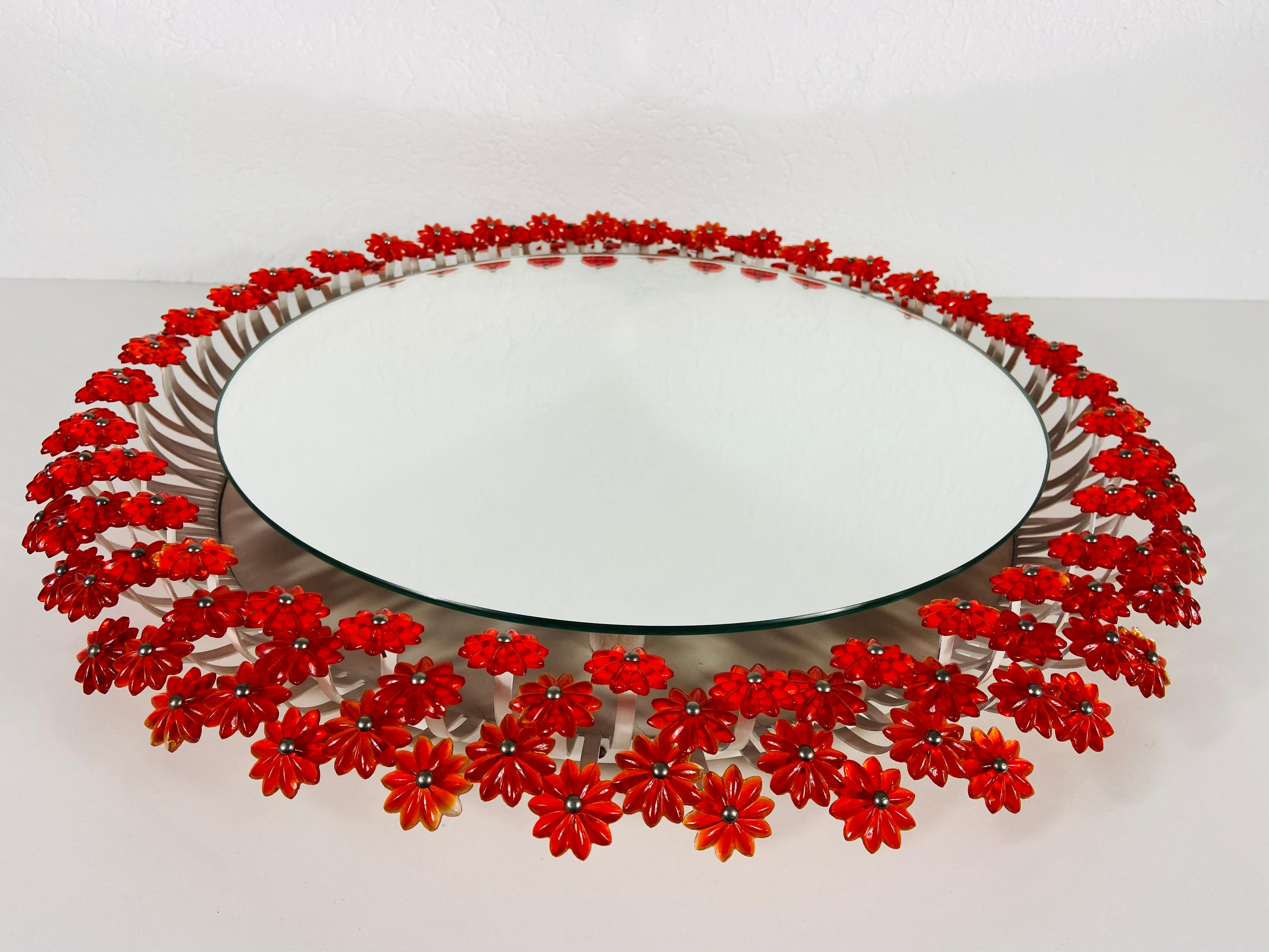 An illuminated wall mirror from the 1960s made in Austria. It was designed by Emil Stejnar for Rupert Nikoll. The mirror has a round design with beautiful orange/red acrylic flowers. The mirror is in a very good vintage 

Measures: 

Total