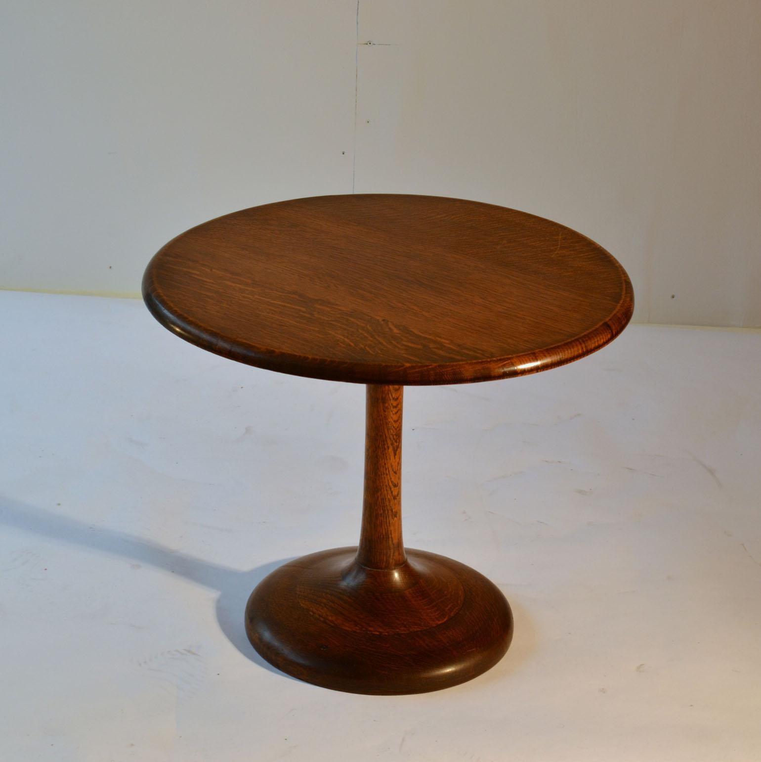 Occasional compact round side table in solid oak on tulip foot. The top has a smooth edge. The table has a polished finish and is in excellent condition.