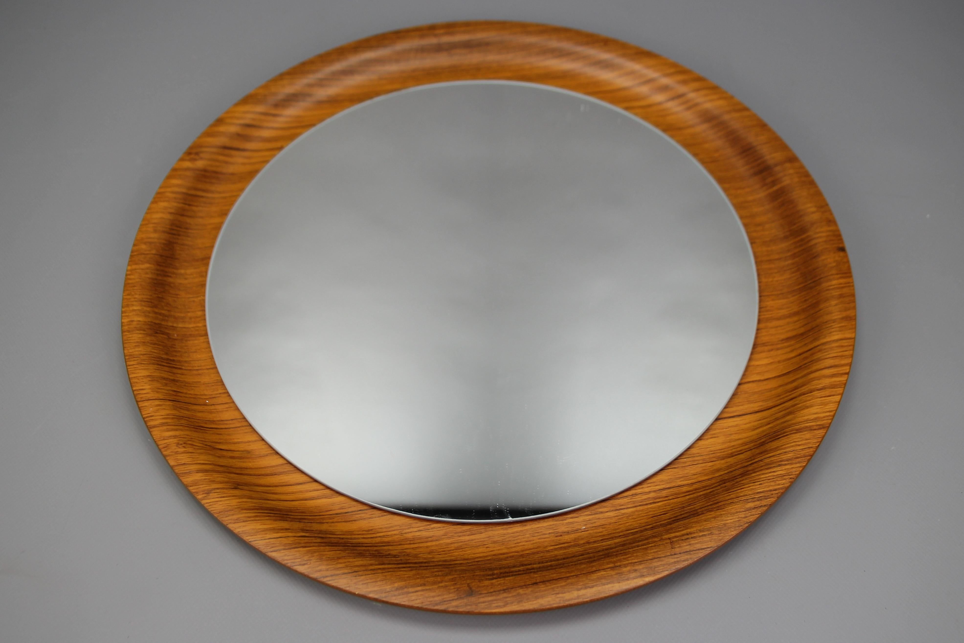 Mid-Century Modern round plywood frame wall mirror, Germany, circa the 1960s.
Vintage wall mirror on an adorable circular plywood curved shape edge frame. 
Dimensions: diameter: 45 cm / 17.71 in; depth: 2.5 cm / 0.98 in.
In good condition with