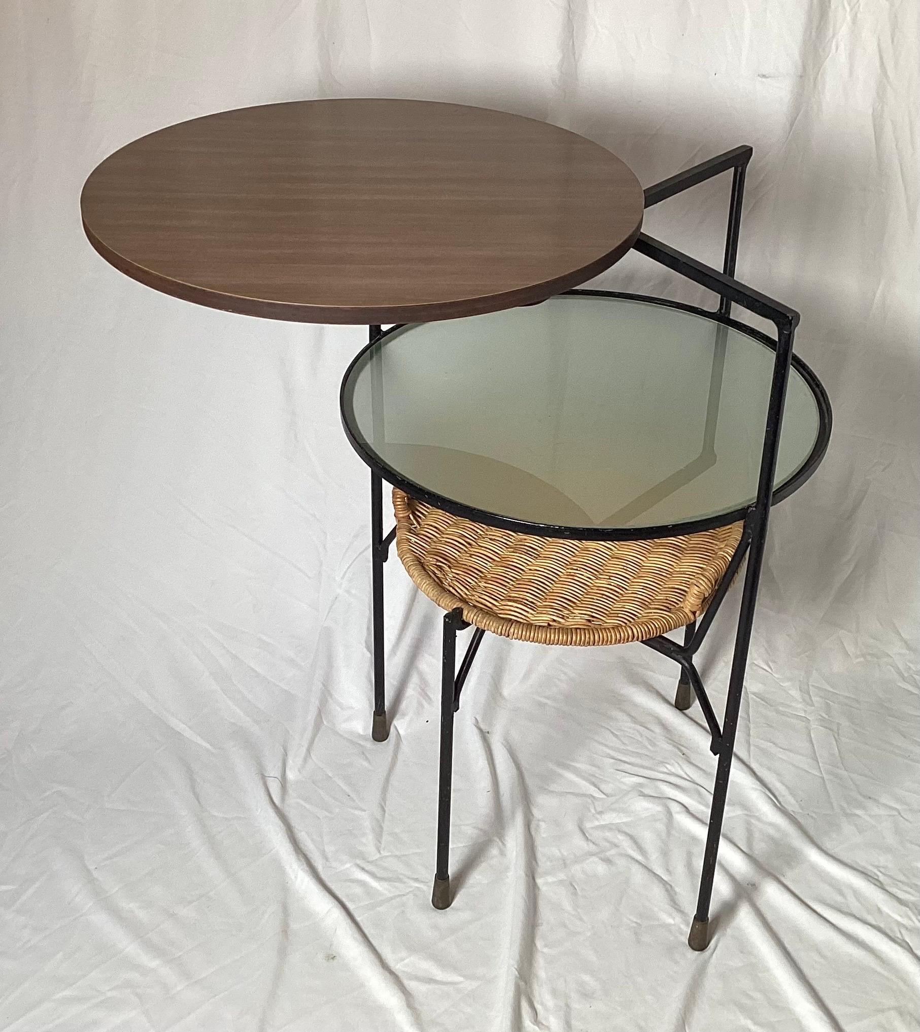 A three tiered round 1970's swivel top table, the first tier in Formica, the middle tier in frosted glass and the lower is hand woven wicker tray. The top which swivels outward. Very good original condition. Measures: 31 high, 20 inches in diameter.