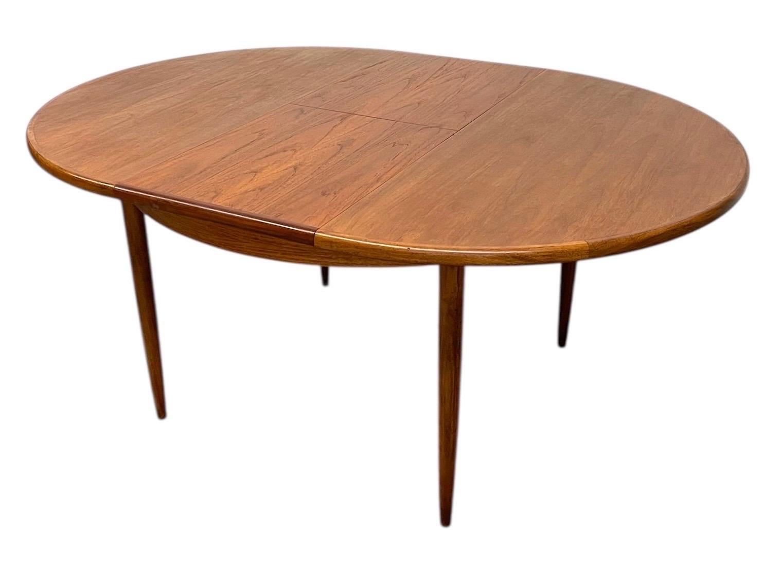 A new vintage mid-century modern dining table in the style of G-Plan's Fresco line, imported from the UK. This versatile piece features a round top that smoothly extends to an oval with the addition of a hidden butterfly leaf stored within the