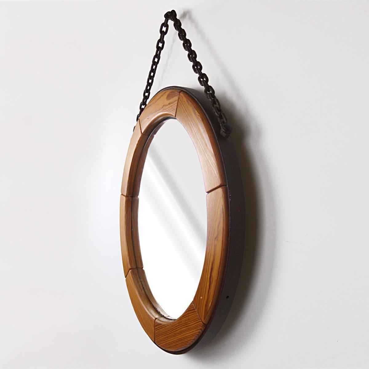 Heavy round mirror in 7 wood segments set in a wrought-iron frame. 
A stylish brutalist detail is the steel chain to hang the mirror on the wall.
Probably of Scandinavian origin.