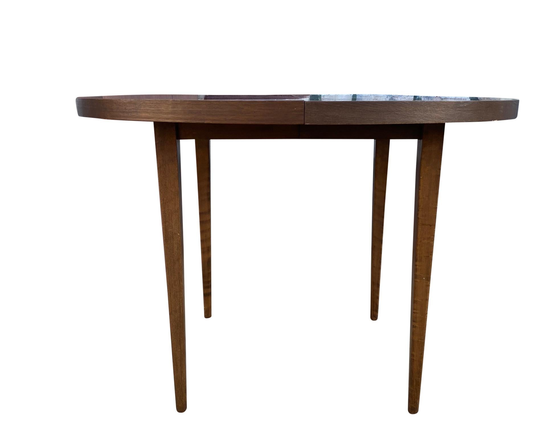 A Mid-Century Modern round walnut extension dining table designed by Paul McCobb for Planner Group Furniture. The table features solid maple with a walnut stain with 4 solid maple lets. The table is in great original vintage condition. Great design.