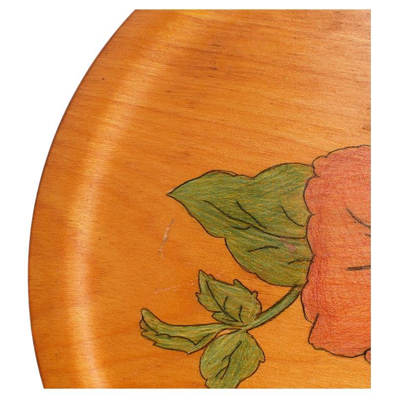 A beautiful round MCM wood botanical motif tray. The tray is round and features a painted pink and red hibiscus with green leaves at the center. The bottom has no markings. However, we believe that it comes from Mexico. This lovely piece of barware