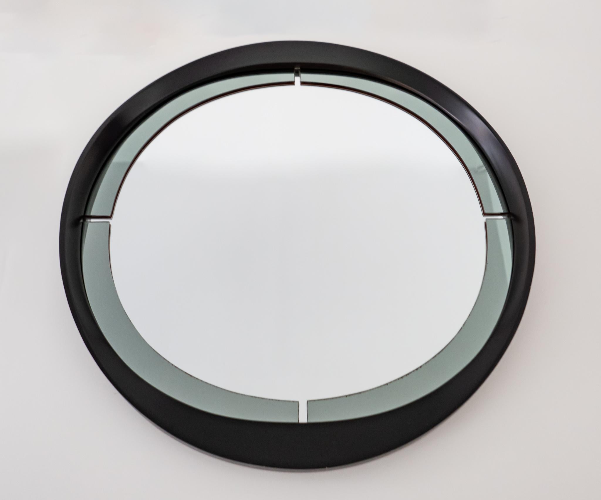 Mid-Century Modern round wooden smoked glass wall mirror, Italy 1970s.

An elegant and rare large round Italian wall mirror made of a two-layered glass. The layer of the mirror frame features grey smoked glass which has 4 cutouts on the left and