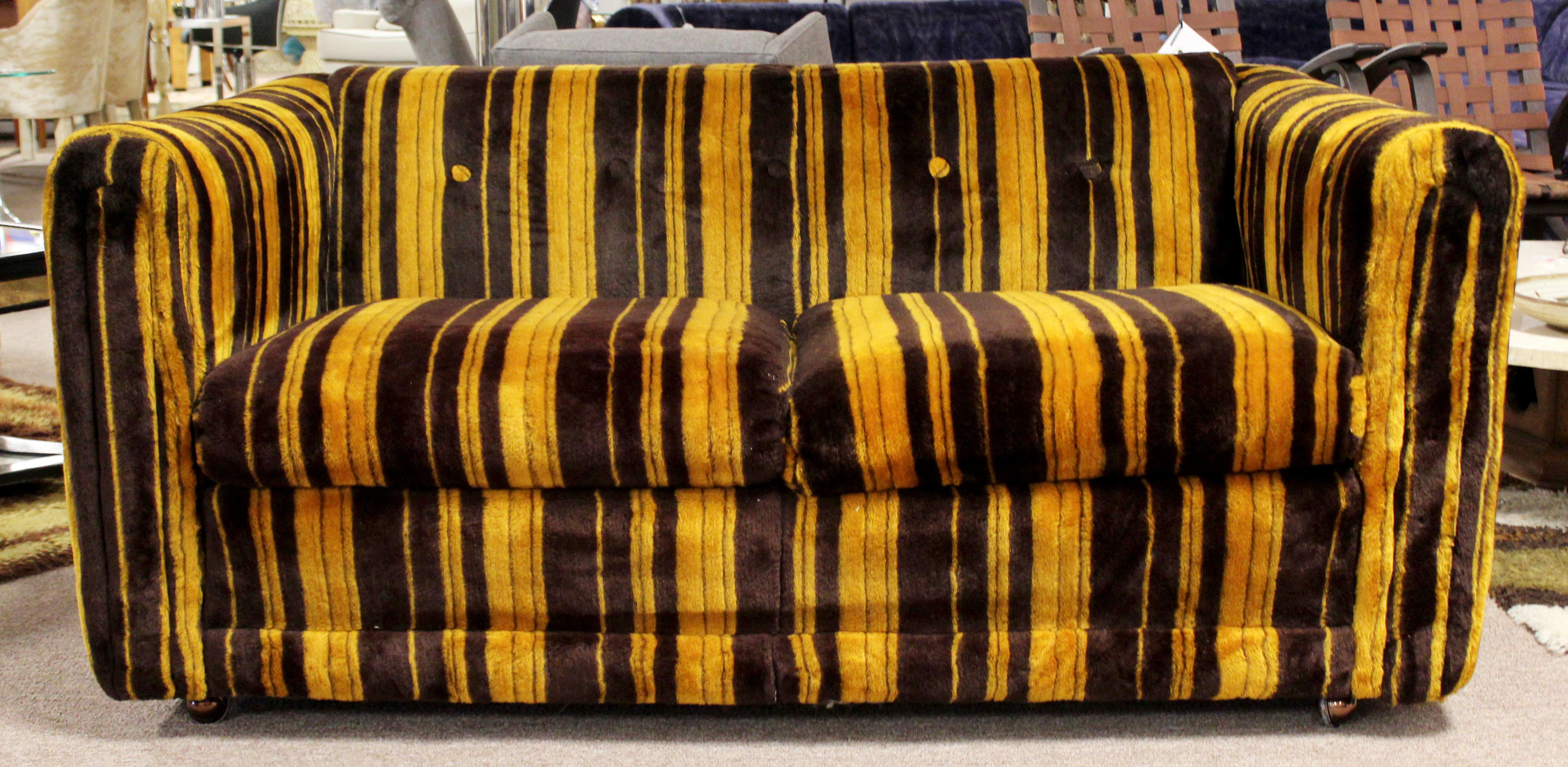 For your consideration is a vibrant pair of orange and brown, tufted sofas on casters, by Rowe Furniture, in the style of Milo Baughman, circa 1970s. In excellent condition. The dimensions are 57
