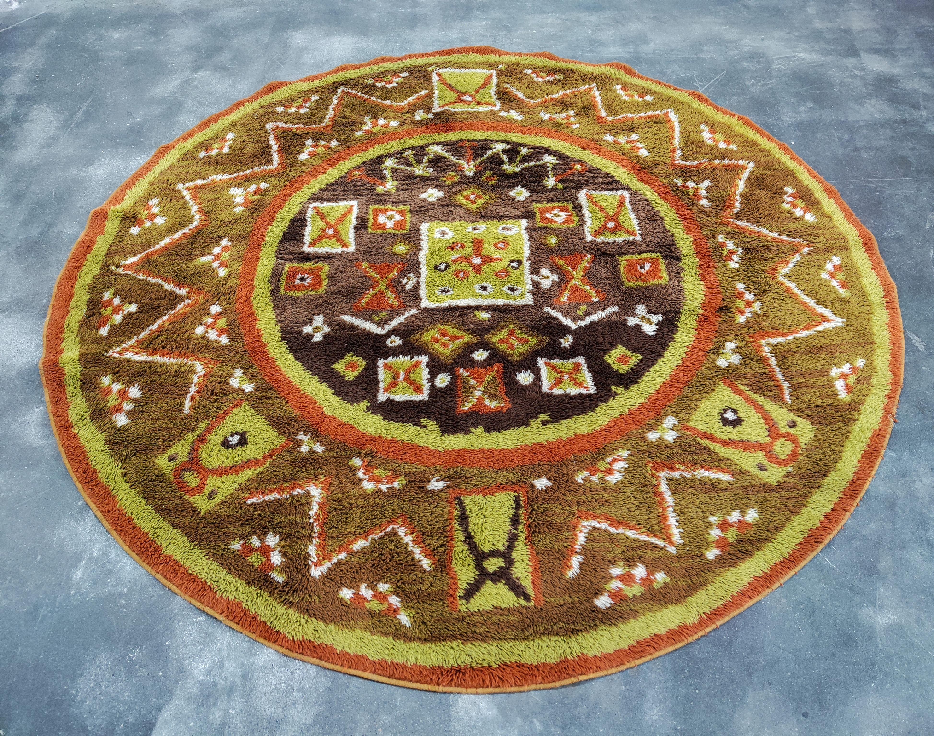 In this listing you will find a round Mid-Century Modern area rug, featuring traditional Nordic symbols. The rug was manufactured by Teppich Siegel, large German rug manufacturer of the time. The rug is called FINLANDIA, which can be seen on the