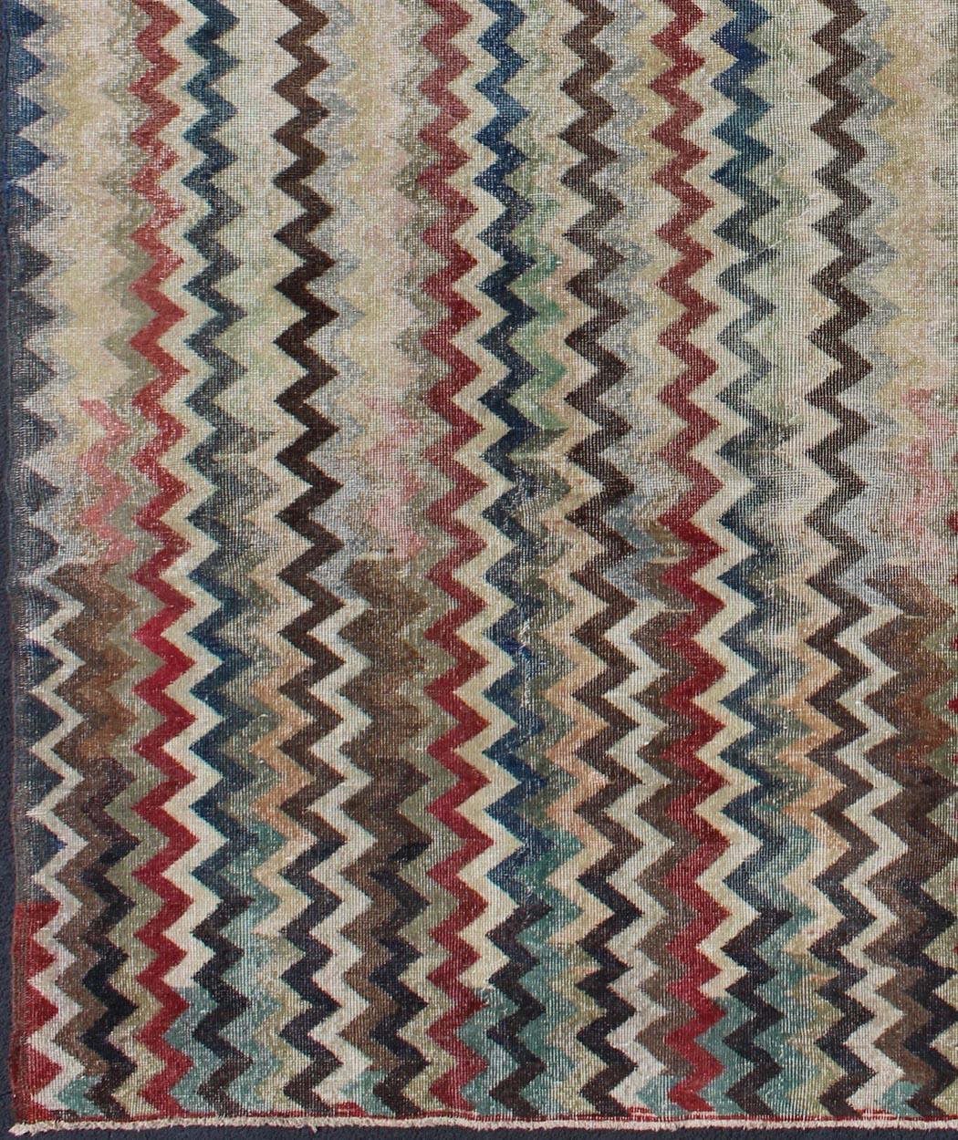 Rendered in zig-zag lines that run parallel to each other amidst an assortment of rich colors, this very unique Vintage Turkish rug showcases a Mid-Century modern design in navy, red, green, brown & cream colors.
Measures: 7'4 x 9'11.
