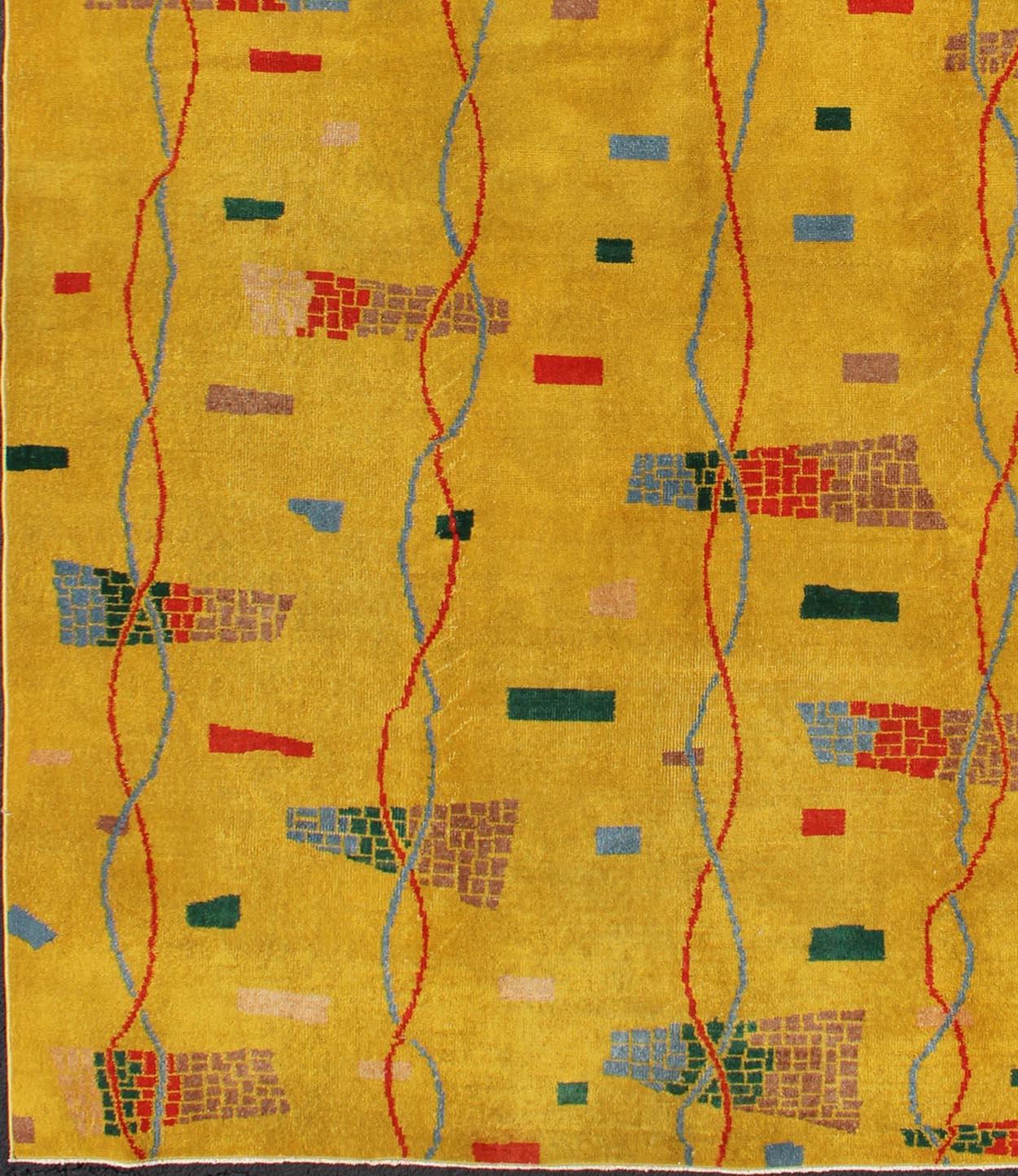 This beautiful Mid-Century rug rests on a saturated yellow background with brilliant accent colors. The design consists of intertwined threads running along the length of the piece, passing through small brick designs along the way. This piece is