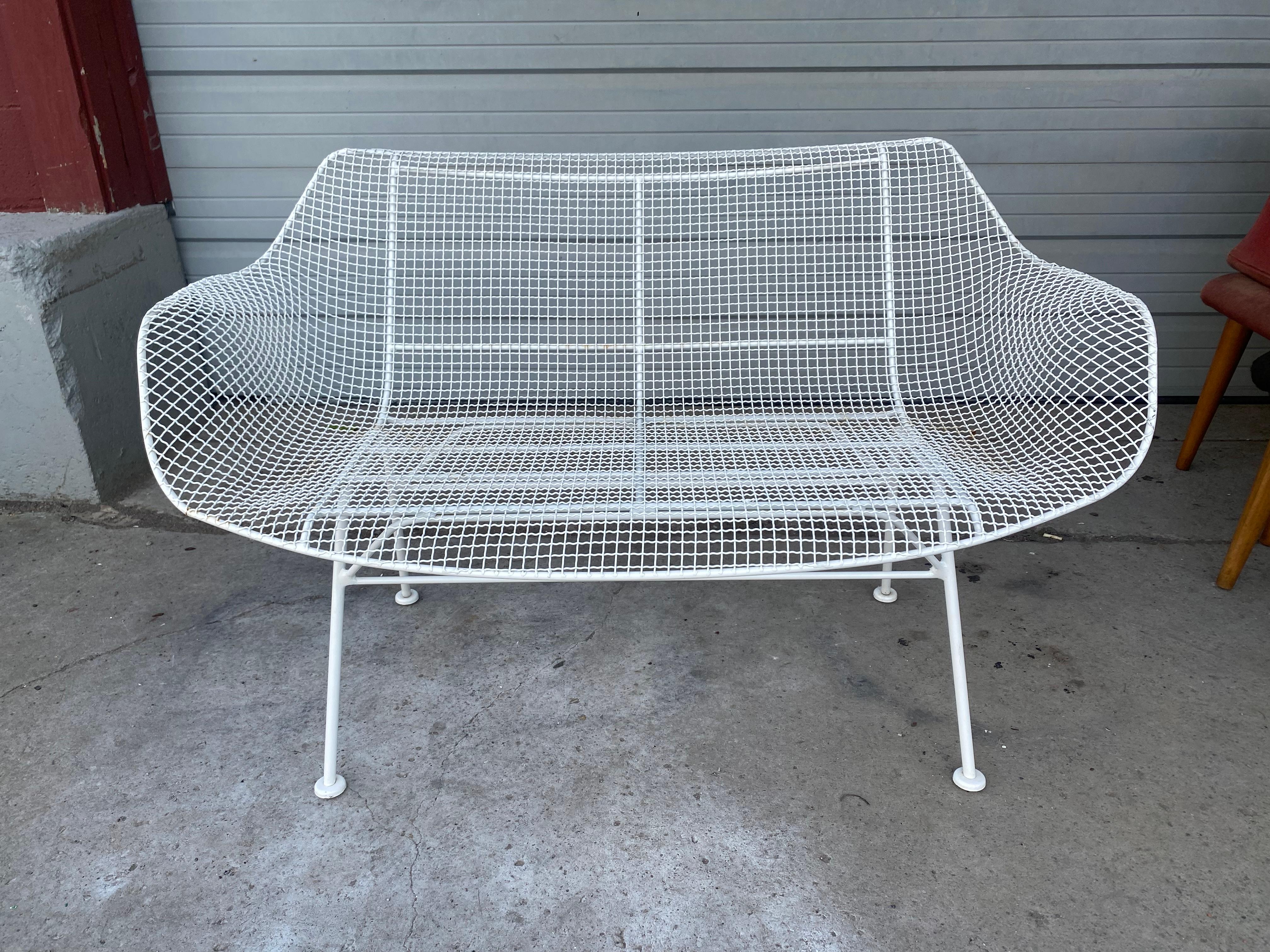 Offered here is a seldom seen, vintage outdoor bench / settee by Russell Woodard Sculpture It has a wrought iron frame with a low-slung woven mesh steel seat made to withstand all weather conditions. Screams Modernist Design ! Perfect for outdoor