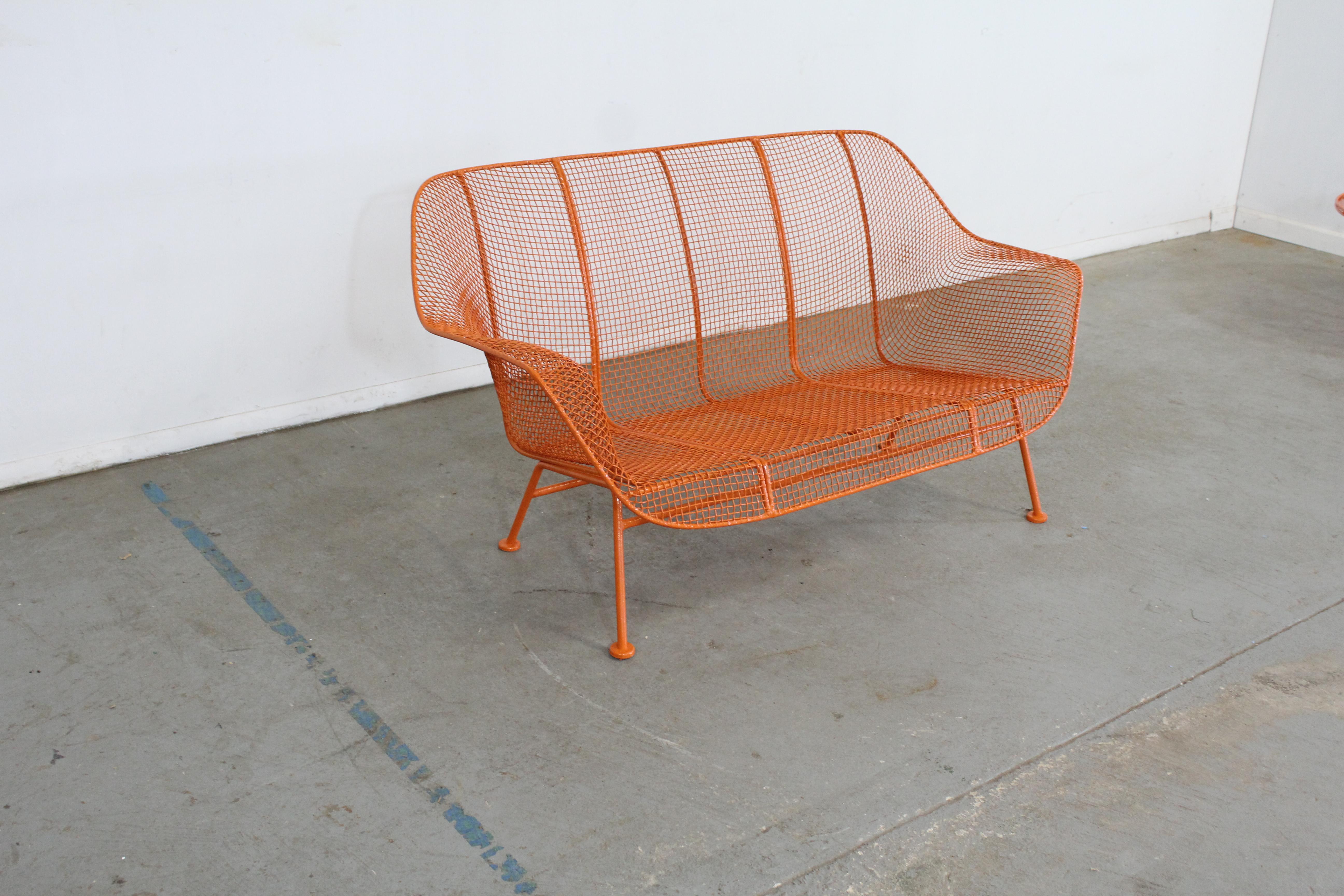 Offered is a vintage outdoor bench by Russell Woodard 'Sculptura'. It has a wrought iron frame with a low-slung woven mesh steel seat made to withstand all weather conditions. Perfect for outdoor lounging. It is in good condition, structurally