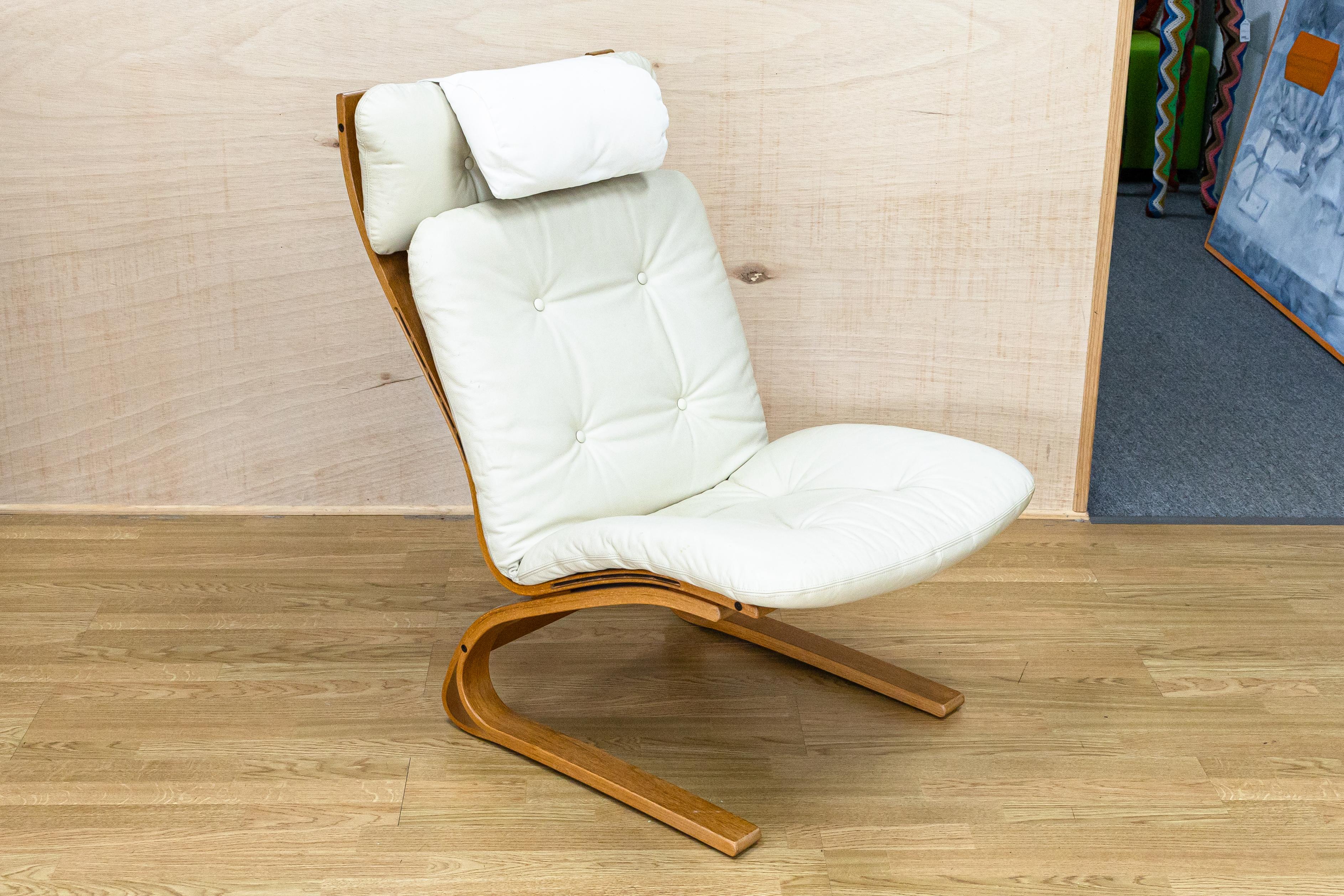 A sophisticated Mid-Century Modern Rybo Rykkin leather lounge chair & ottoman from Norway. This lounge chair is made with a light wood frame and is upholstered in white leather cushions. The cushions on both the chair and ottoman and attached via