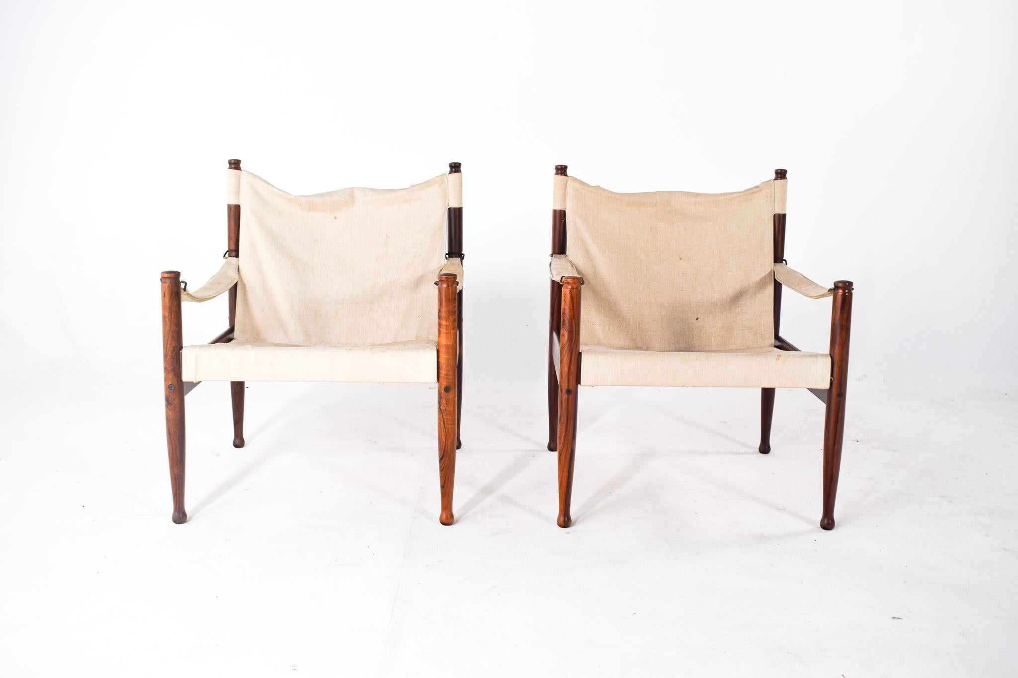 The image depicts a pair of Danish mid-century ‘safari’ chairs, which are iconic in their simplistic yet elegant design. They were designed by Erik Wørts for Niels Eilersen and are recognized as model number 30, a product of the 1960s. These chairs