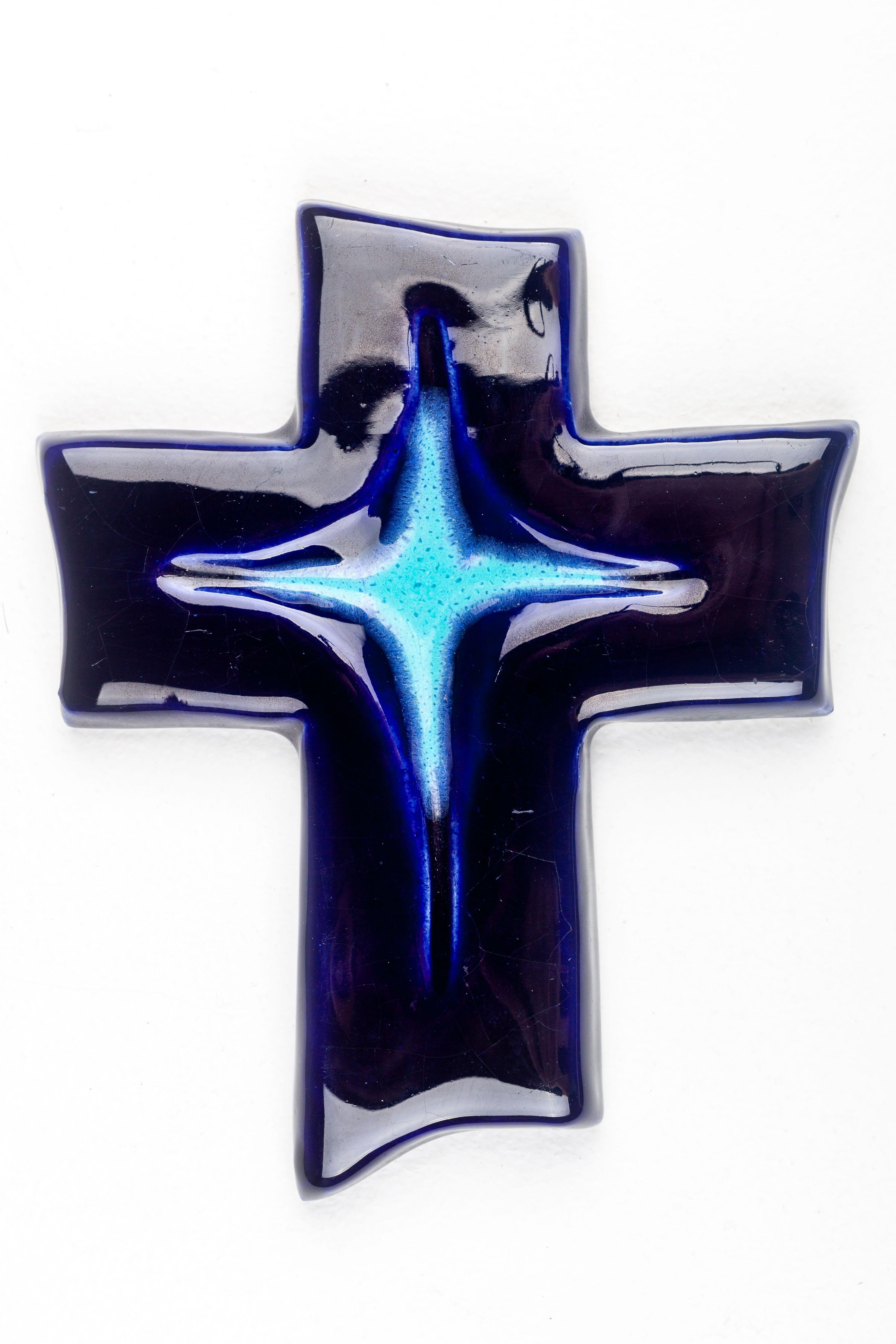 This striking mid-century modern wall cross, handcrafted by a European studio pottery artist, is a significant representation of the era's design principles, which favored simplicity, organic forms, and innovative use of materials. The cross is