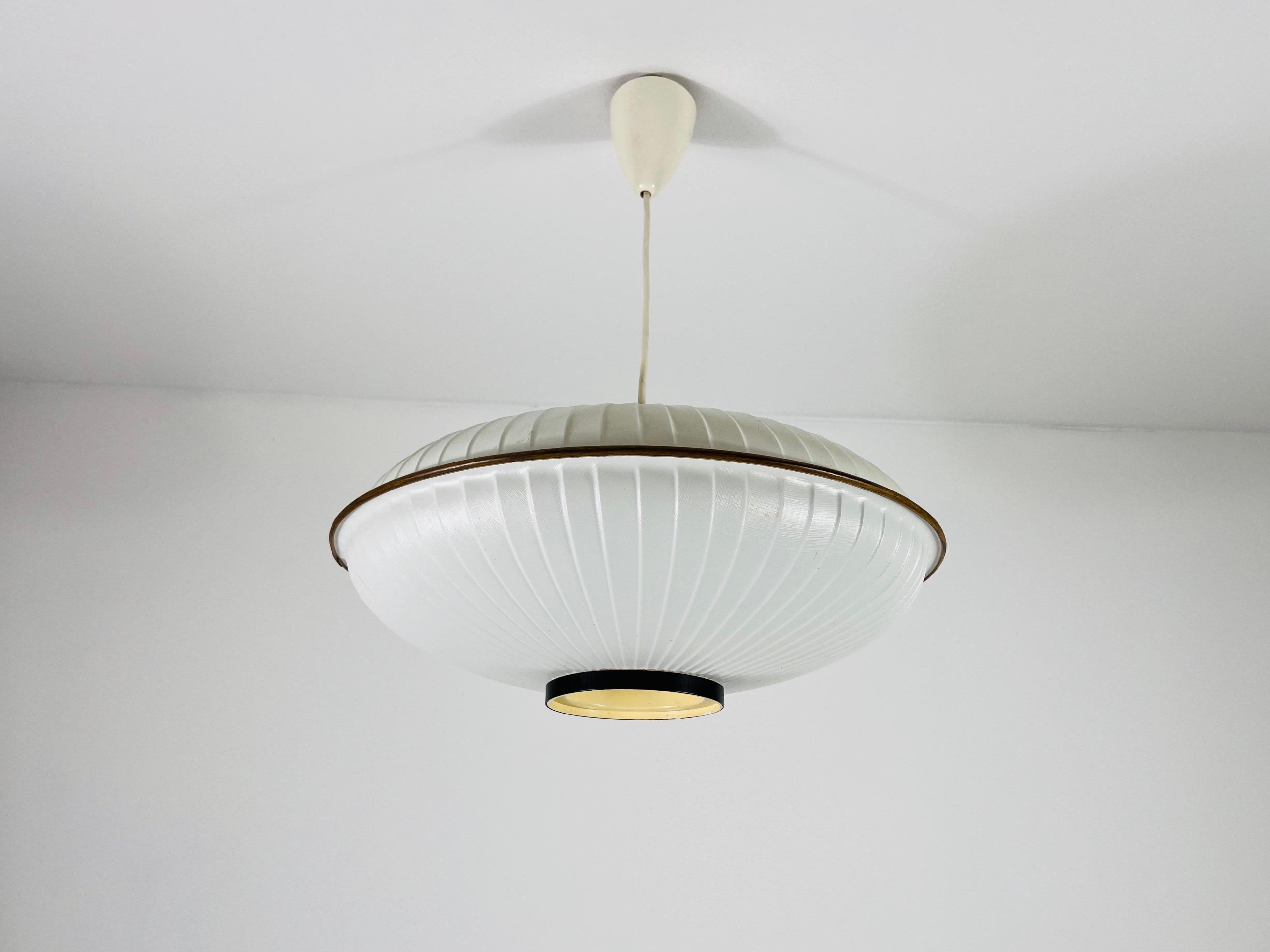 Presenting a saucer-shaped pendant lamp from the 1960s, embodying minimalist Italian design. This elegant fixture features an organic form and emits a warm light that creates a cozy and inviting atmosphere. Its sleek lines and understated style