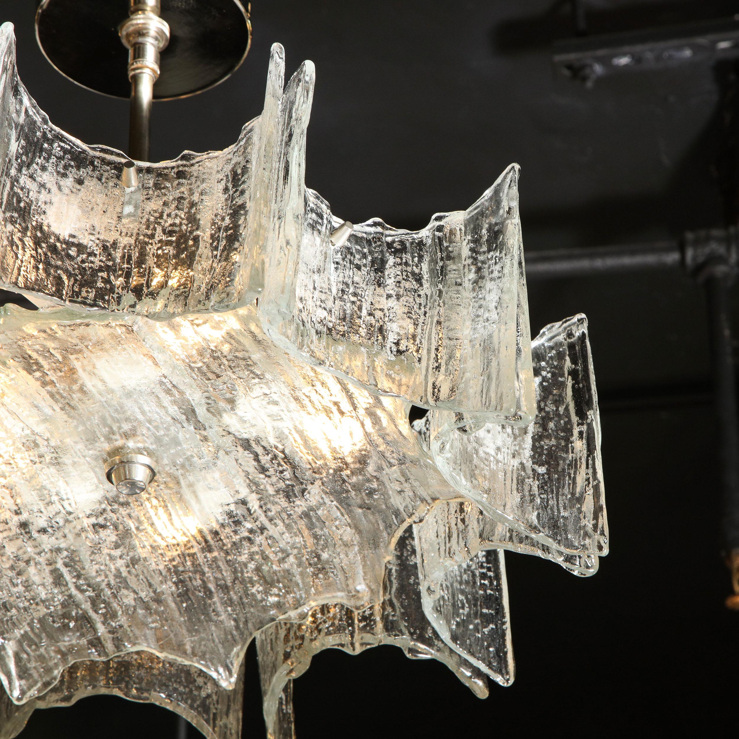This graphic and refined Mid-Century Modern chandelier was designed by the esteemed atelier of J.T. Kalmar of Austria and realized in Murano, Italy circa 1970. They feature a circular bottom plate in textured translucent Murano glass- resembling