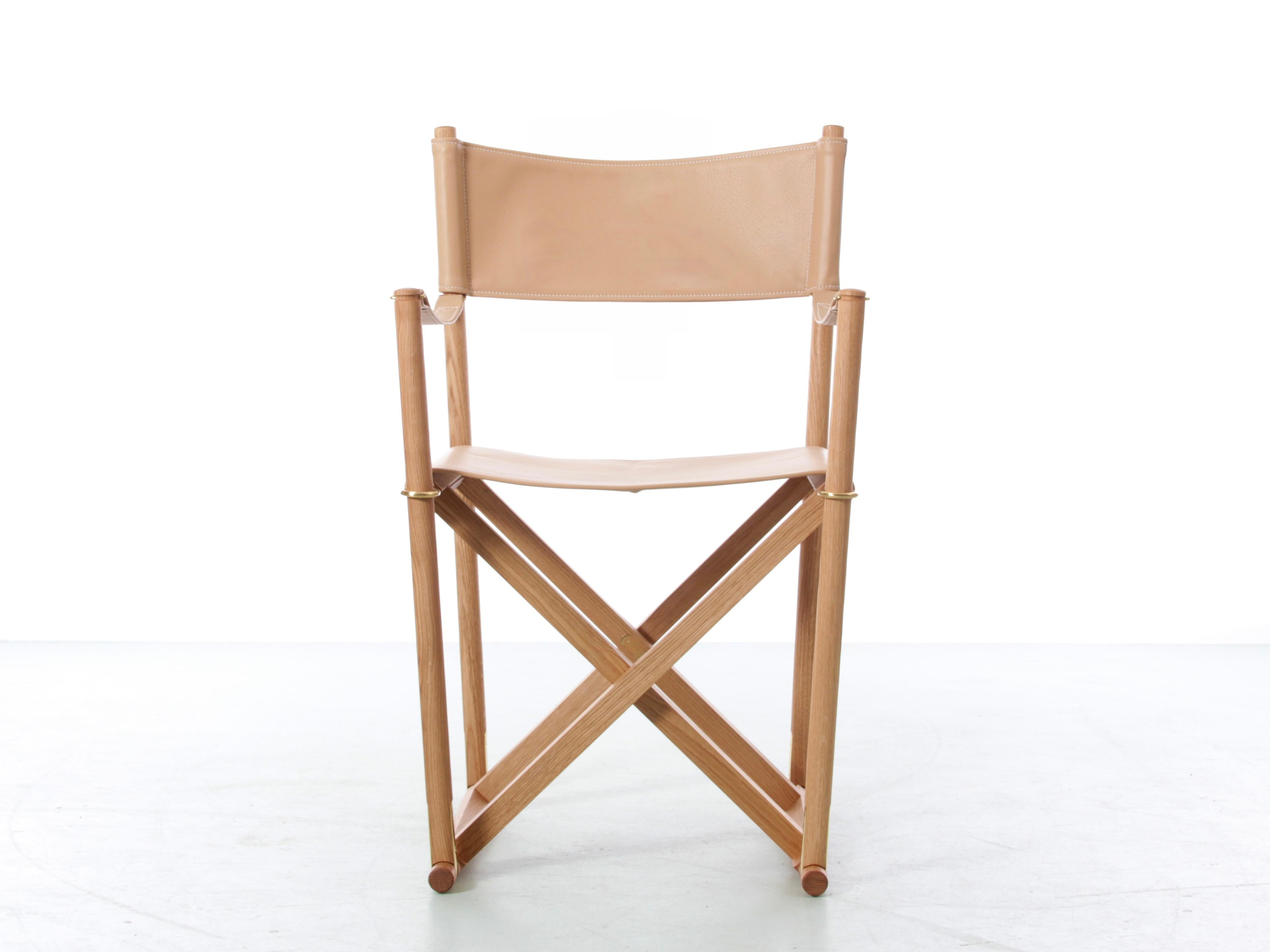 Mogens Koch a conçu la chaise pliante MK16 pour un concours de sièges d'église supplémentaires, réinterprétant le tabouret pliant traditionnel en associant une fonctionnalité de pliage et de stockage facile à une esthétique moderne. Ce concept