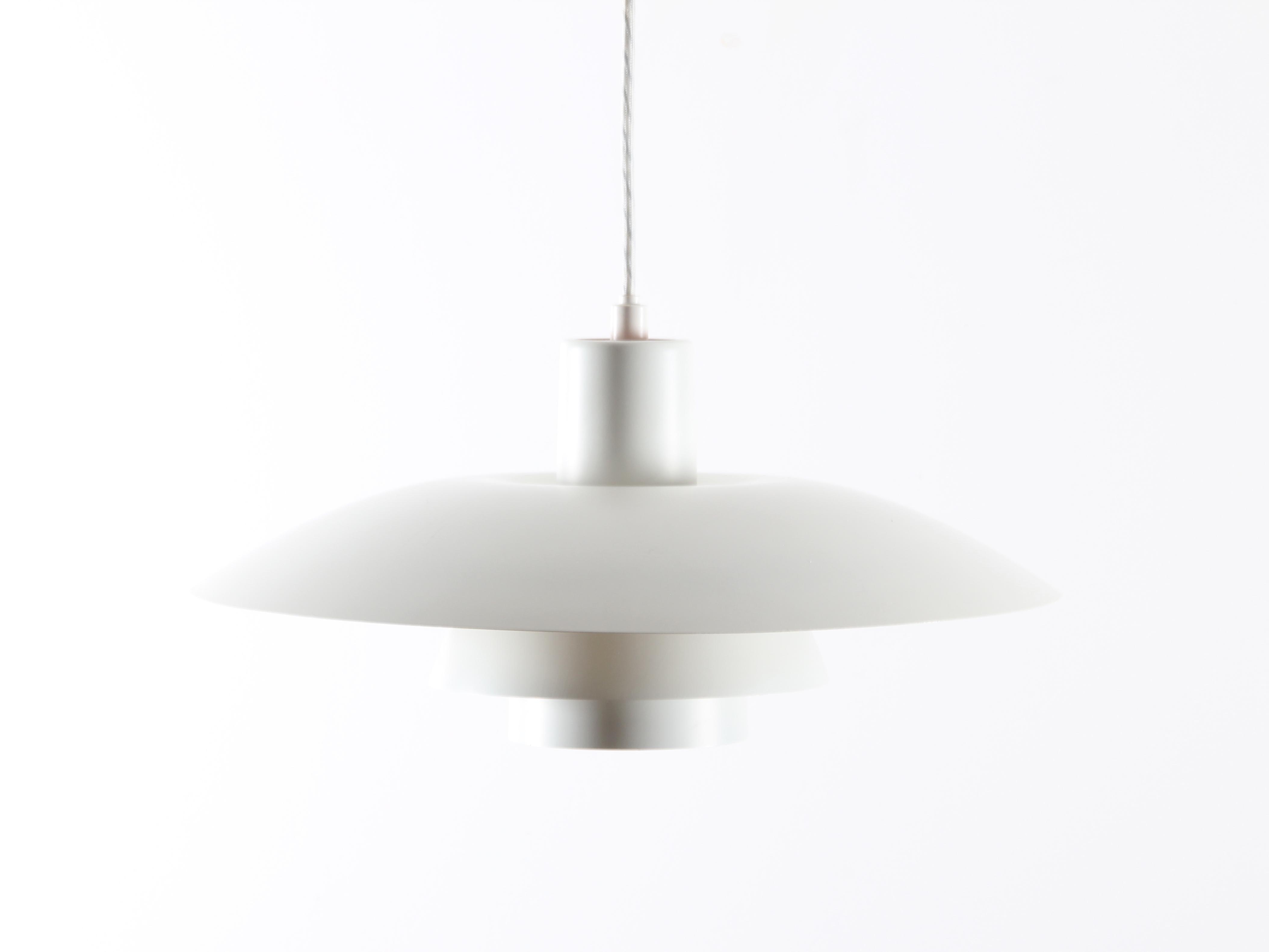 The Modern Scandinavian Pendelleuchte PH 4/3 von Poul Henningsen aus der Jahrhundertmitte. Mattweiß lackiertes Metall. Reflecetur rot. Erzeugt ein weiches und nie blendendes Licht. Weißes Textilkabel.