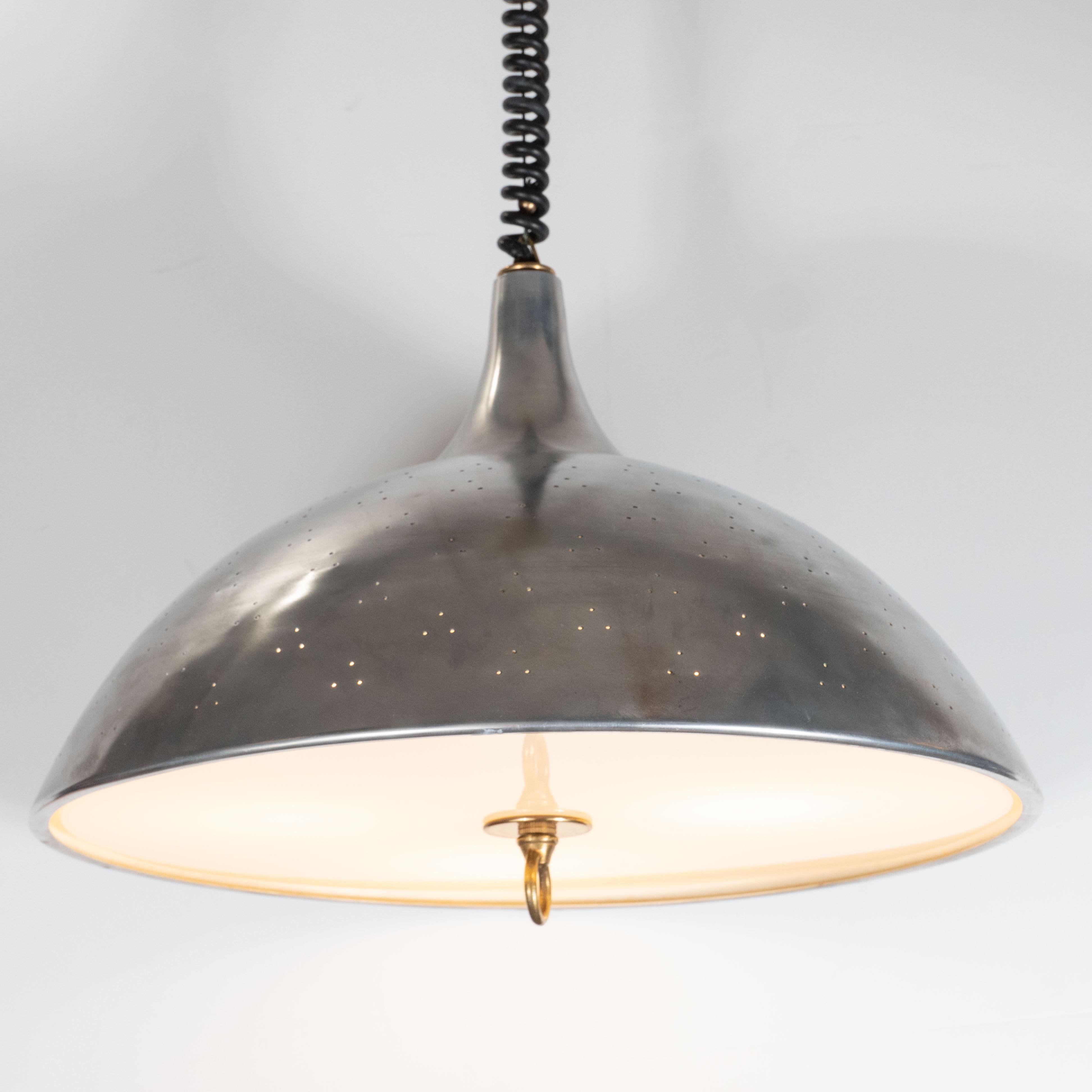 This elegant Mid-Century Modern chandelier was realized in Sweden, circa 1960. It features a domed body with an abundance of perforations presented in triangular sets of three. There is a Lucite shade fitted at the bottom of the fixture secured with
